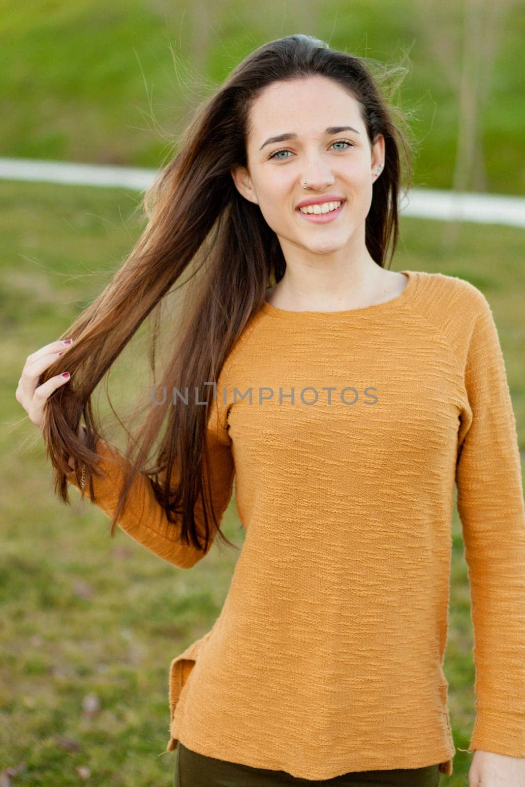 Outdoor portrait of beautiful happy teenager girl laughing while the wind moves her hair