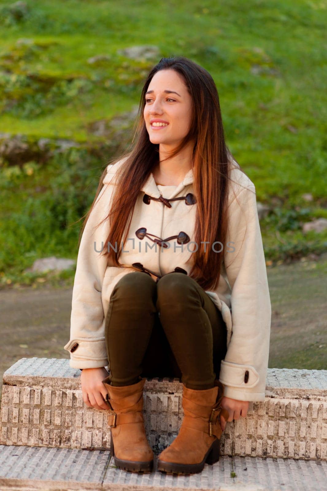 Pretty teenager girl sitting on the sidewalk in a park