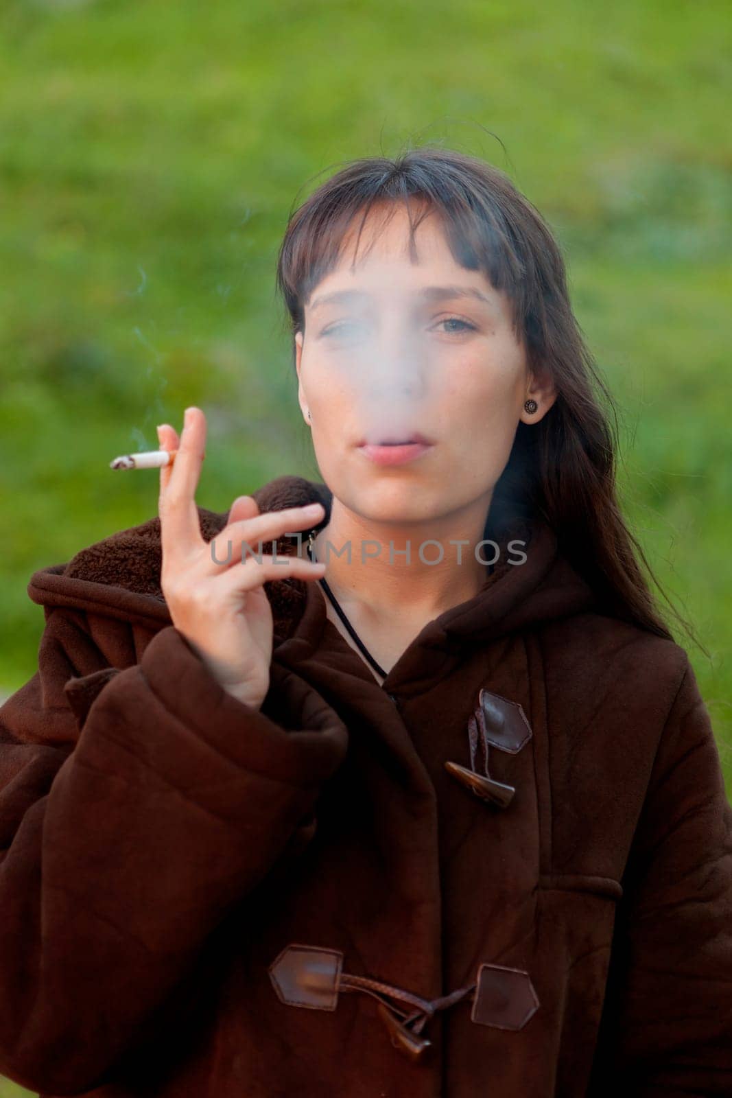 Pretty woman with long hair smoking in the park