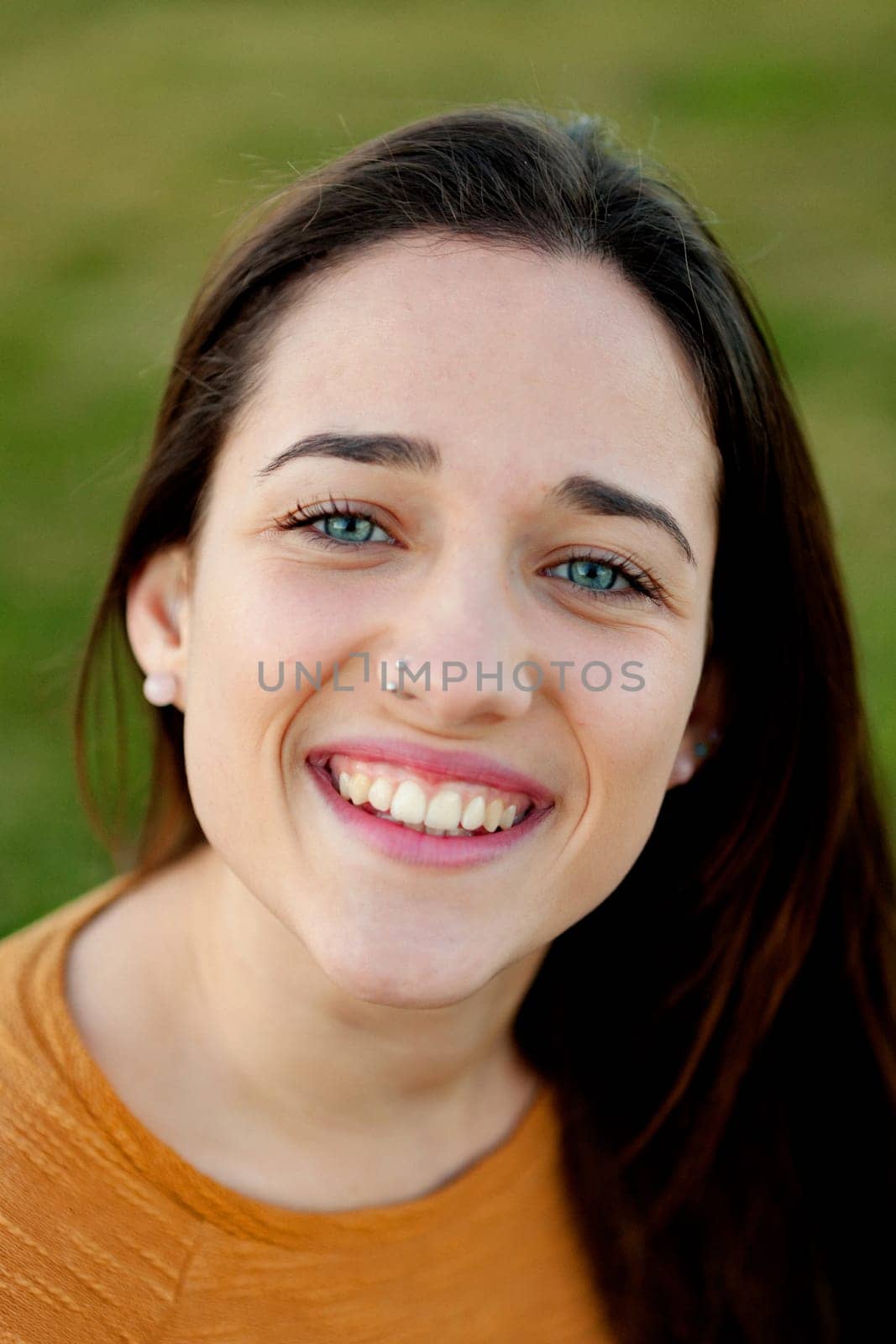 Outdoor portrait of beautiful happy teenager girl laughing with perfect teeth in field