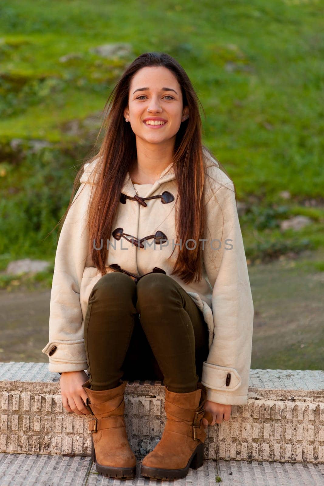 Pretty teenager girl sitting on the sidewalk in a park