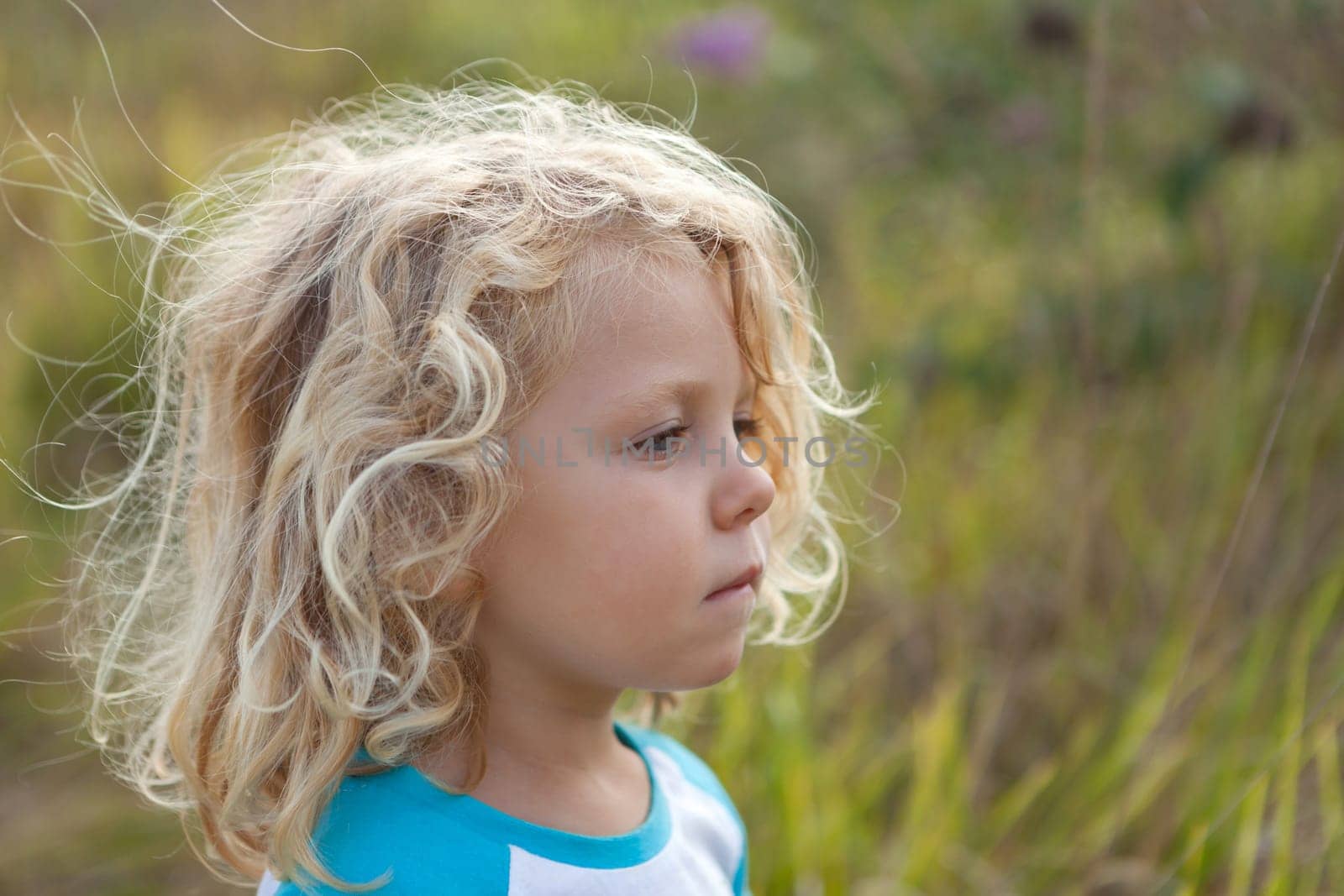Small child with long blond hair enjoying of a sunny day
