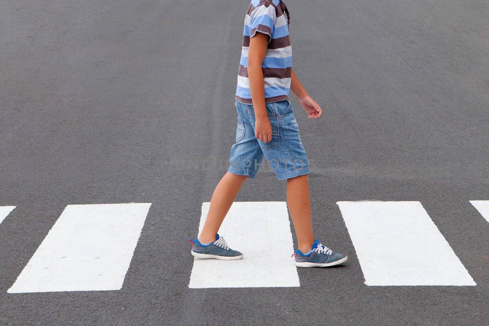 Child crossing the crosswalk on the road