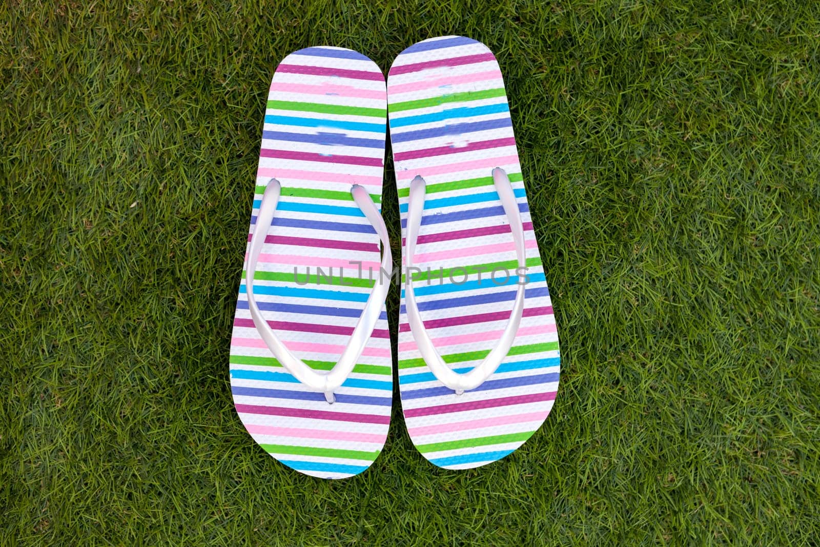 Flip-flops on the green grass of the pool