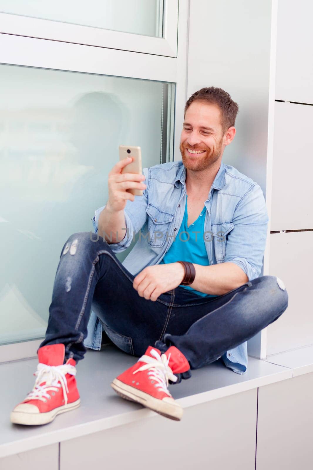 Casual guy next to a vintage bicycle with the mobile wearing denim shirt