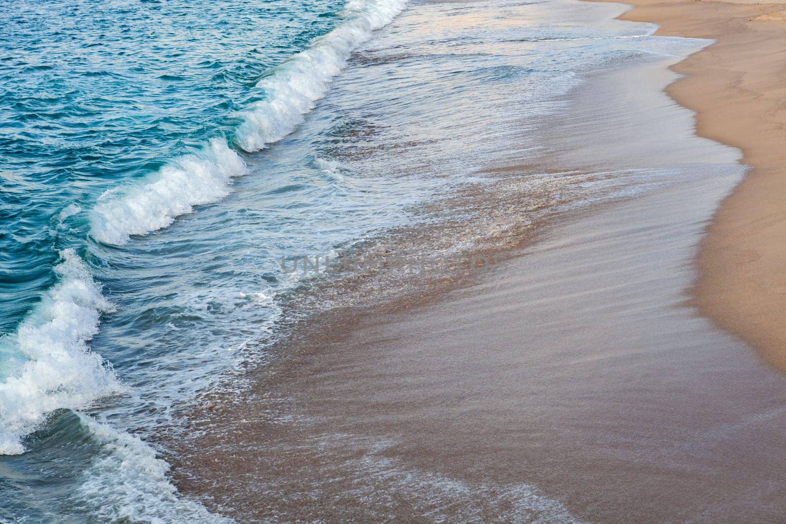 Foamed blue waves breaking in the beach
