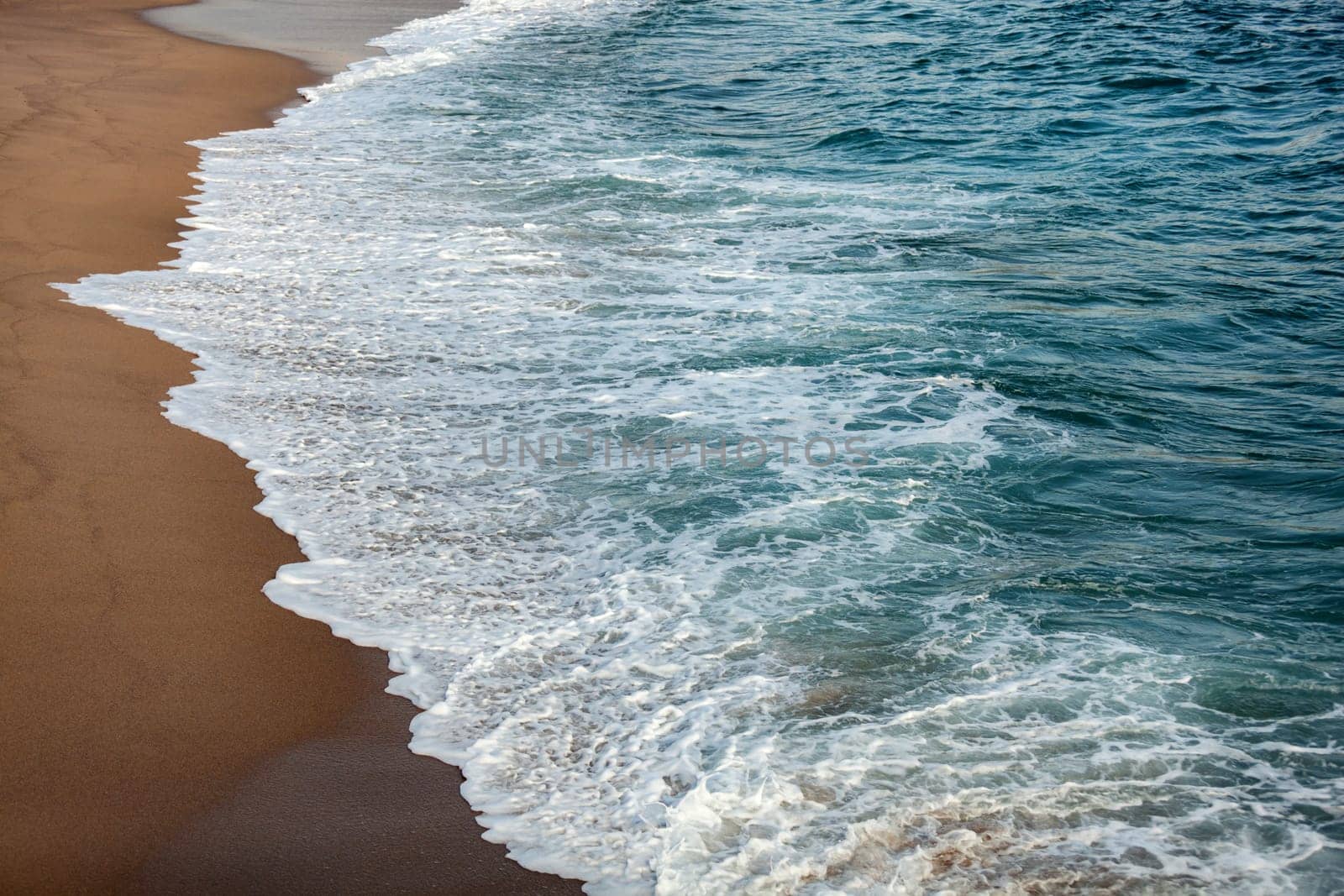 Foamed blue waves breaking in the beach