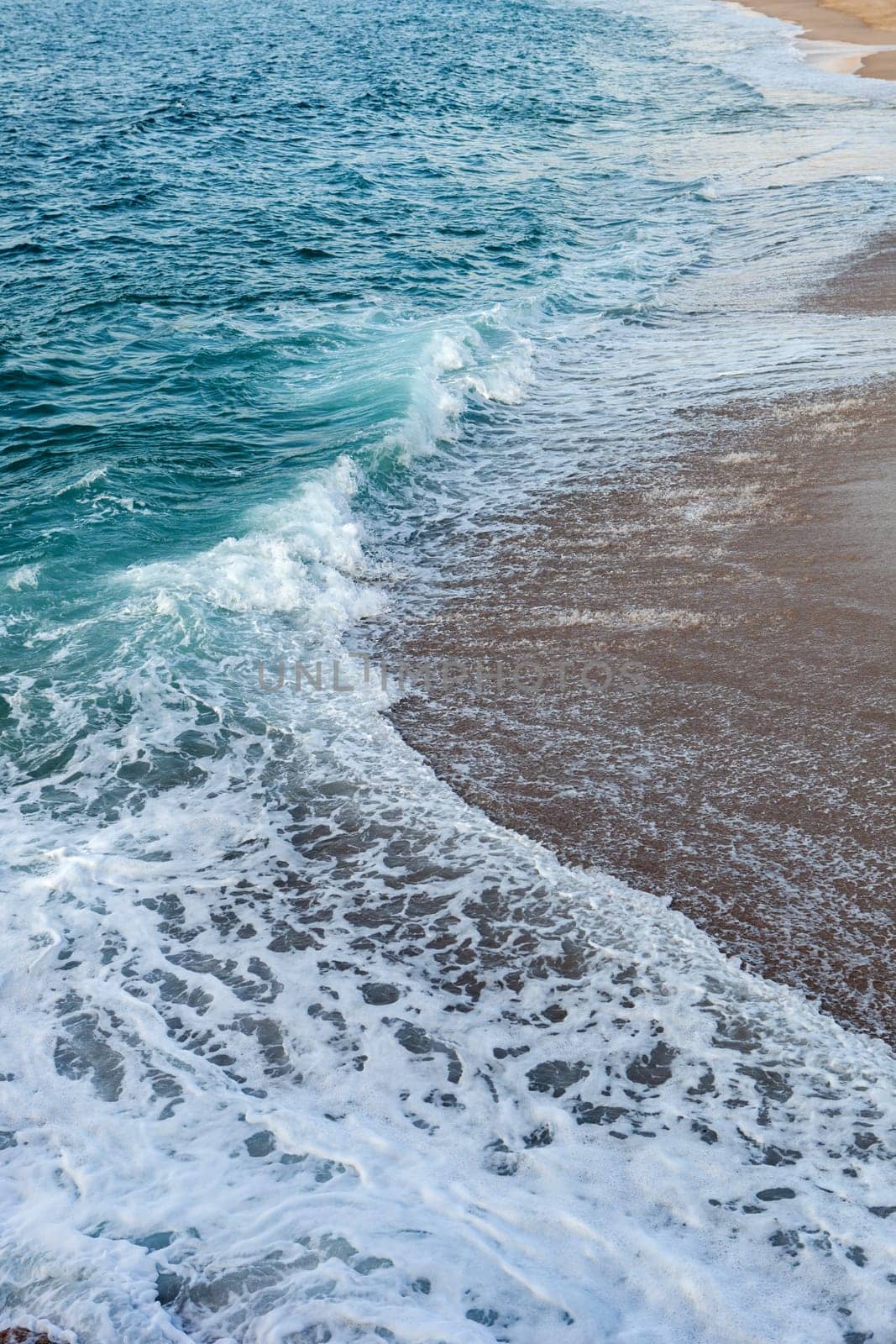 Foamed blue waves breaking in the beach