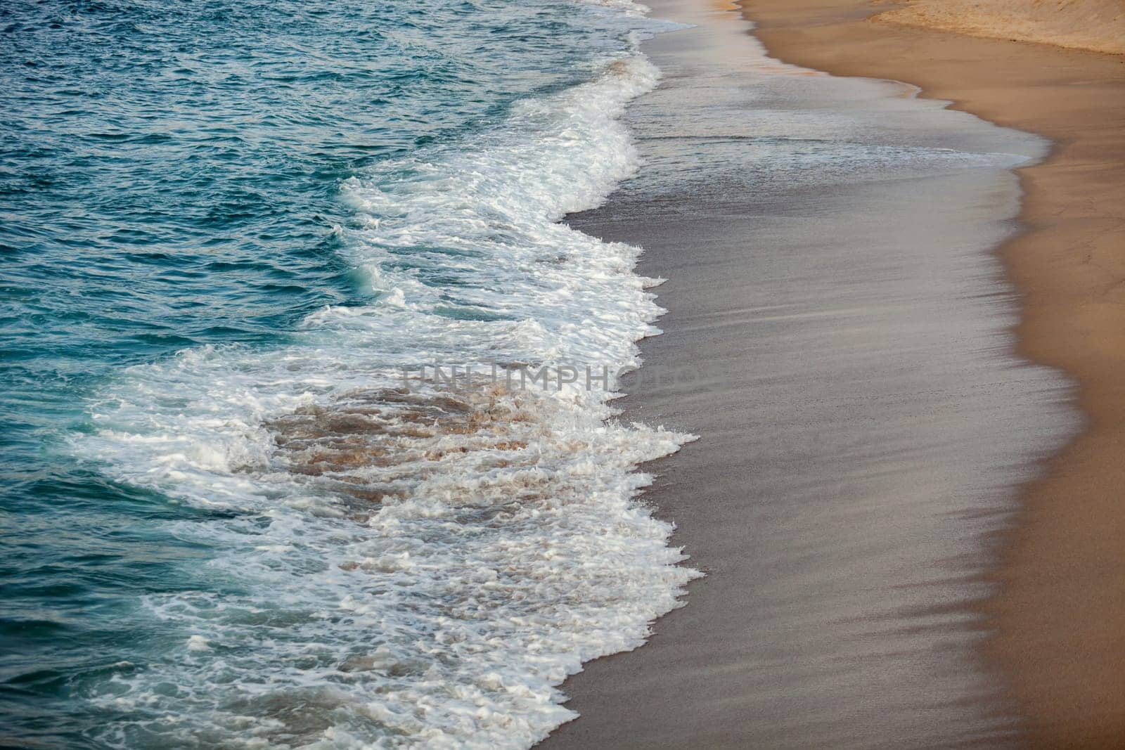 Foamed blue waves breaking in the beach