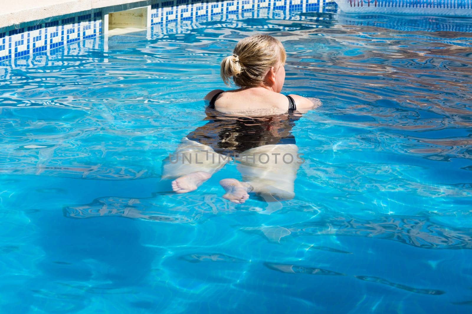 Happy woman relaxing in indoor swimming pool, enjoying spa.