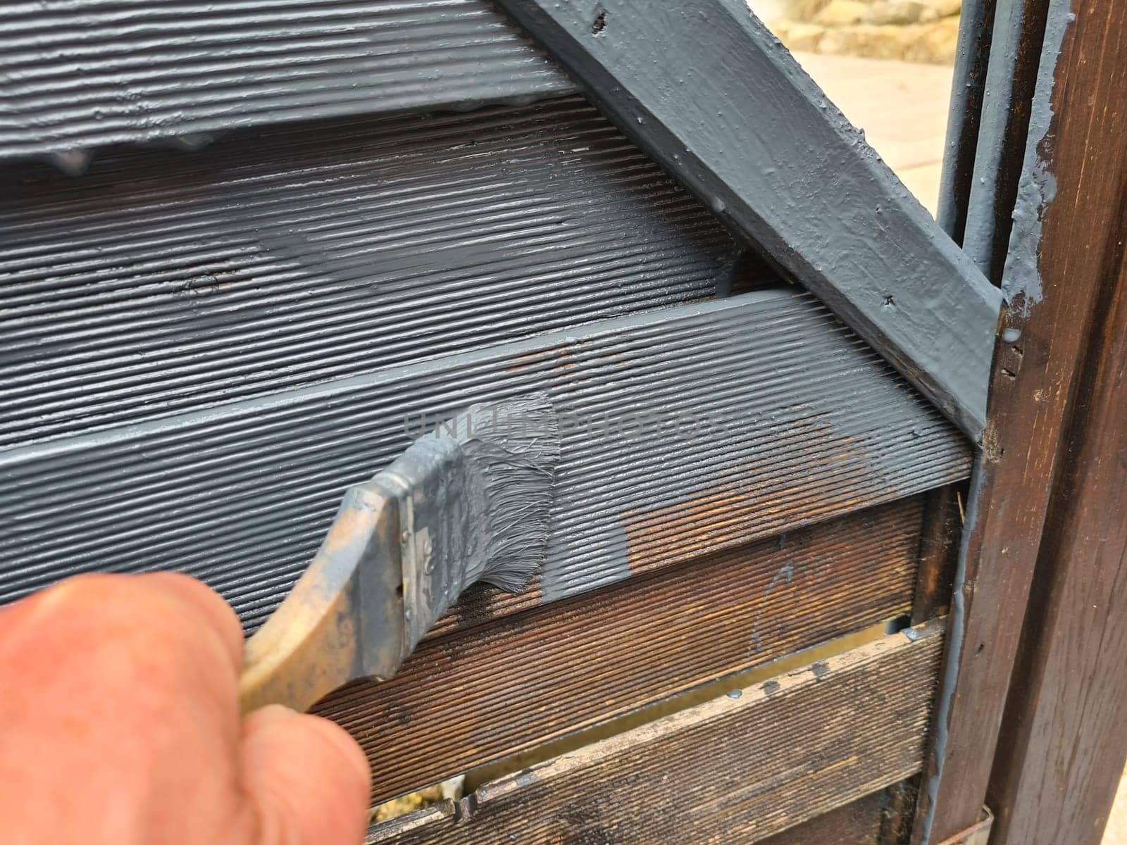 Brushing garden fence with brush - close-up