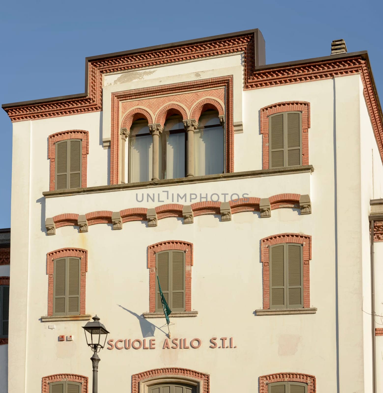 decorated facade of public primary school in old industrial village, shot in winter at Crespi Adda, Capriate, Lombardy, Italy.
