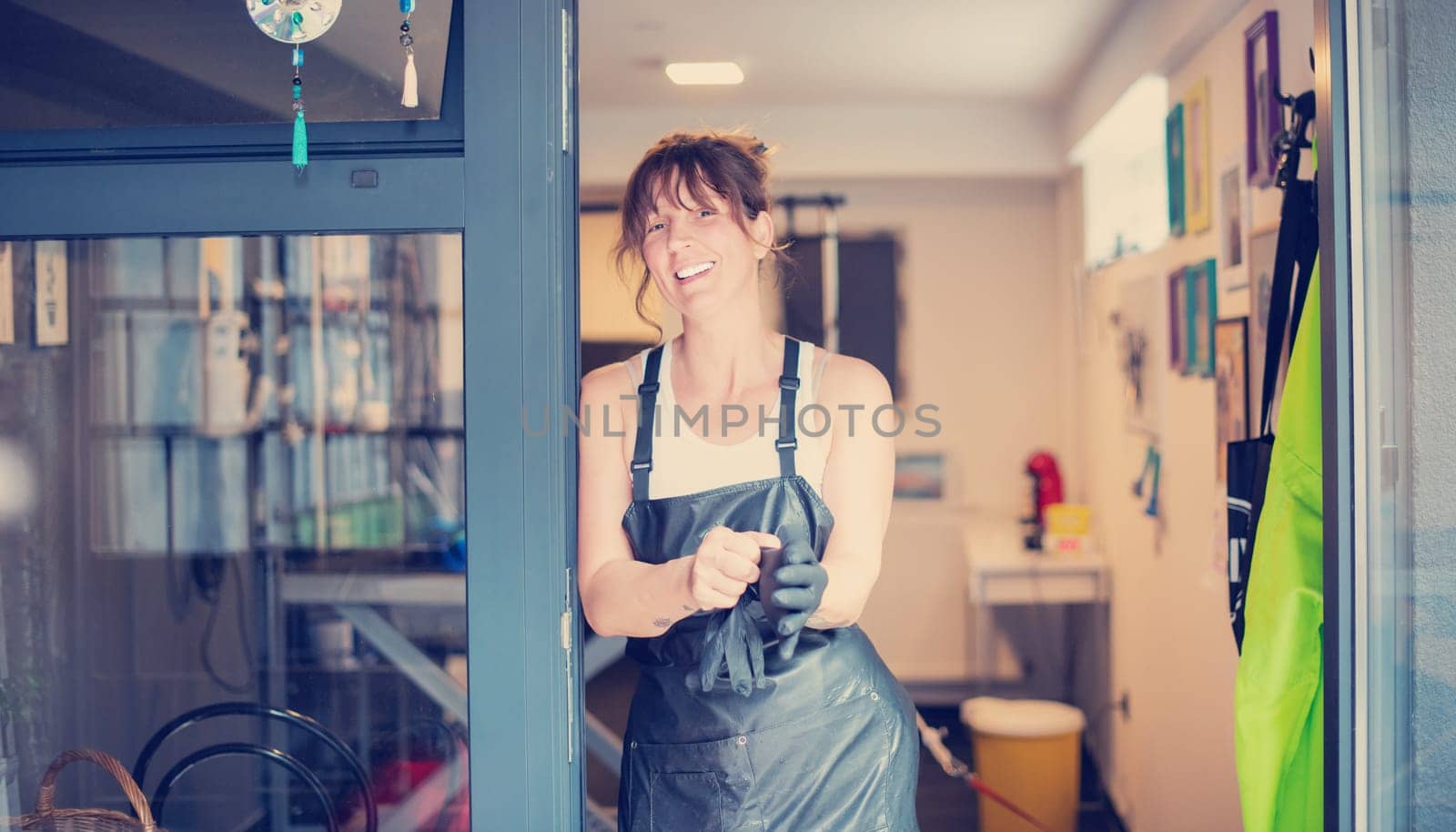 portrait of professional pet hairdresser hipster woman with tattoos while standing at the door of her beauty salon for animals