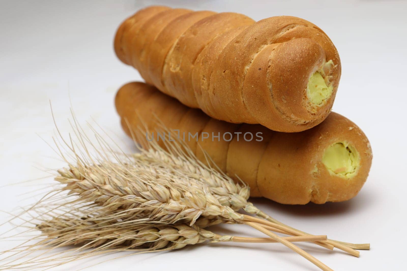 tasty and healthy cream roll and ripe wheat on white background
