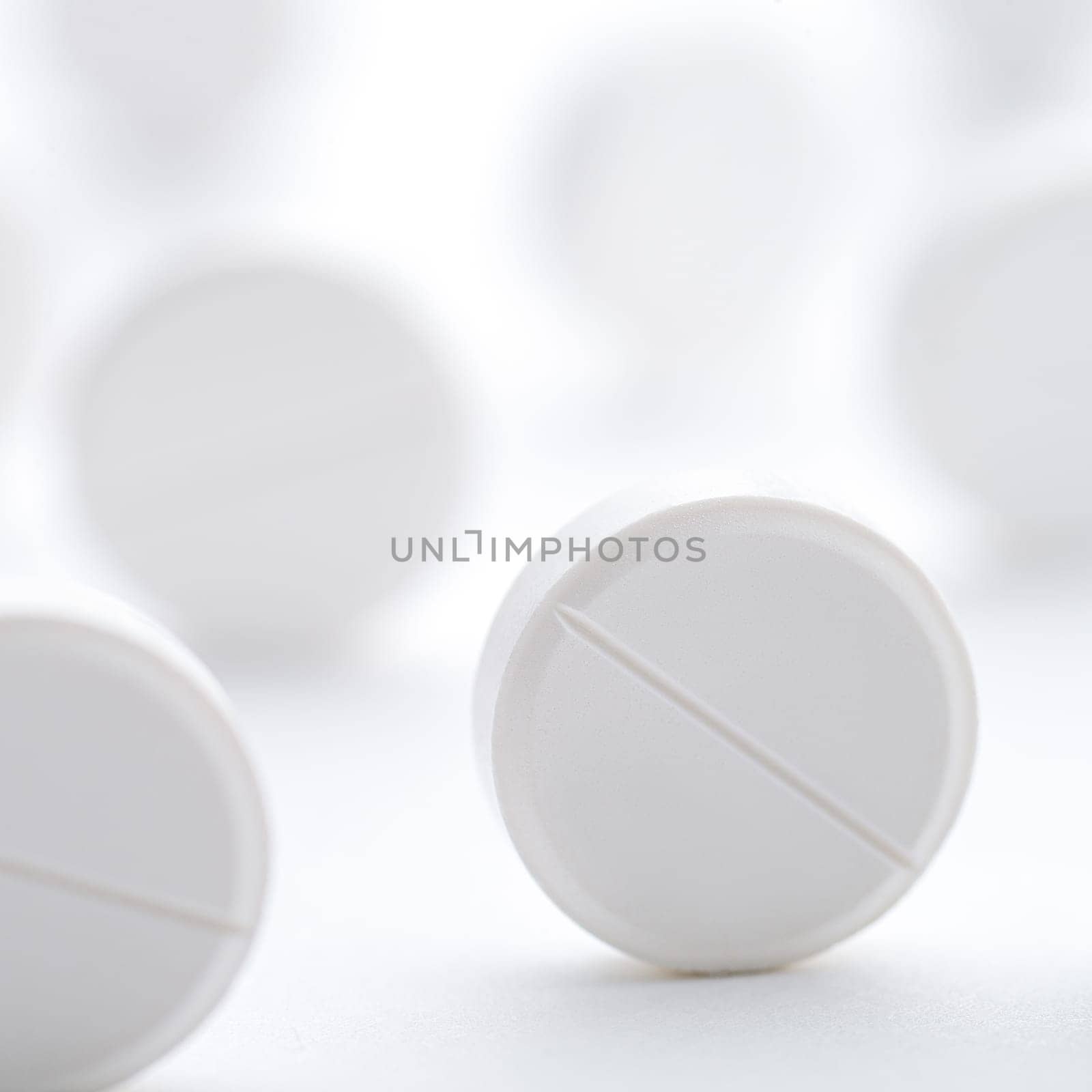 A pile of white pills scattered on a bright white background. Selective focus. Mockup layout, template.