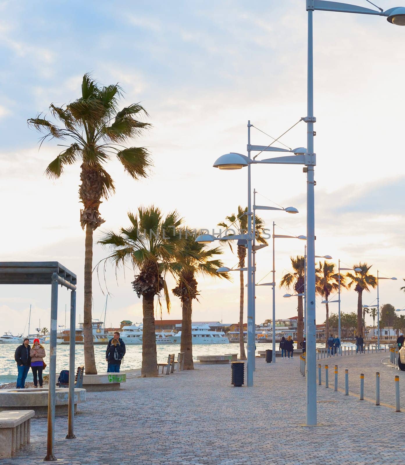PAPHOS, CYPRUS - FEBRUARY 15, 2019: People walking by embankment at beautiful twilight in Paphos