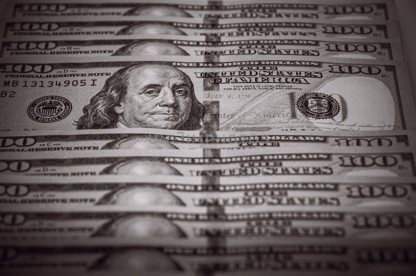 One hundred dollar bills are in a row, one stands out, selective focus. Style black and white.
