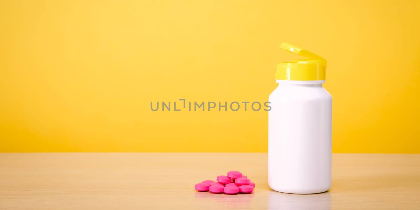 A white jar with scattered red pills on a yellow background. Place for the label, logo, layout.