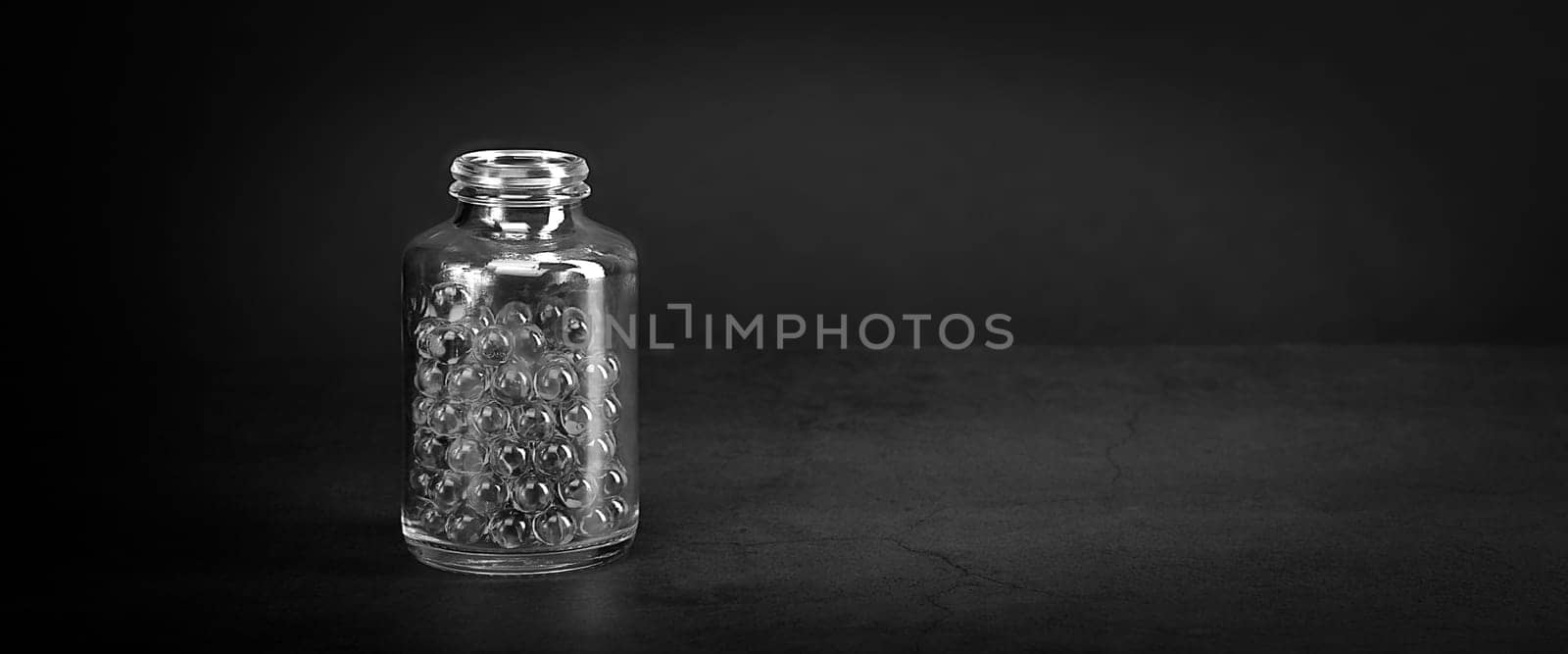 A glass jar with pills on a gray background. Black and White style. Space for lettering, logo, layout.