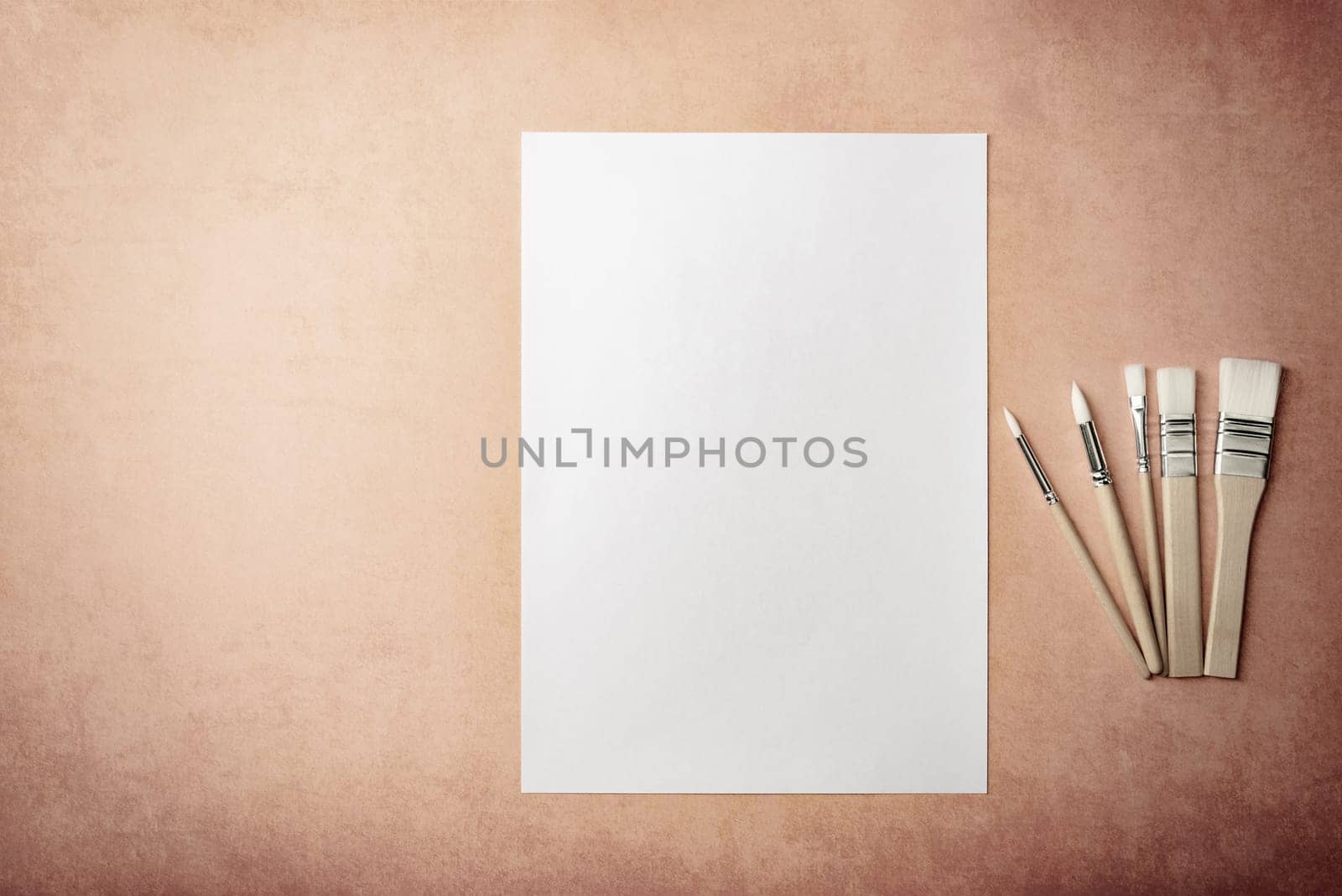 A clean white sheet and brushes on a textured background with space to copy. Layout, mockup space for text and drawing.