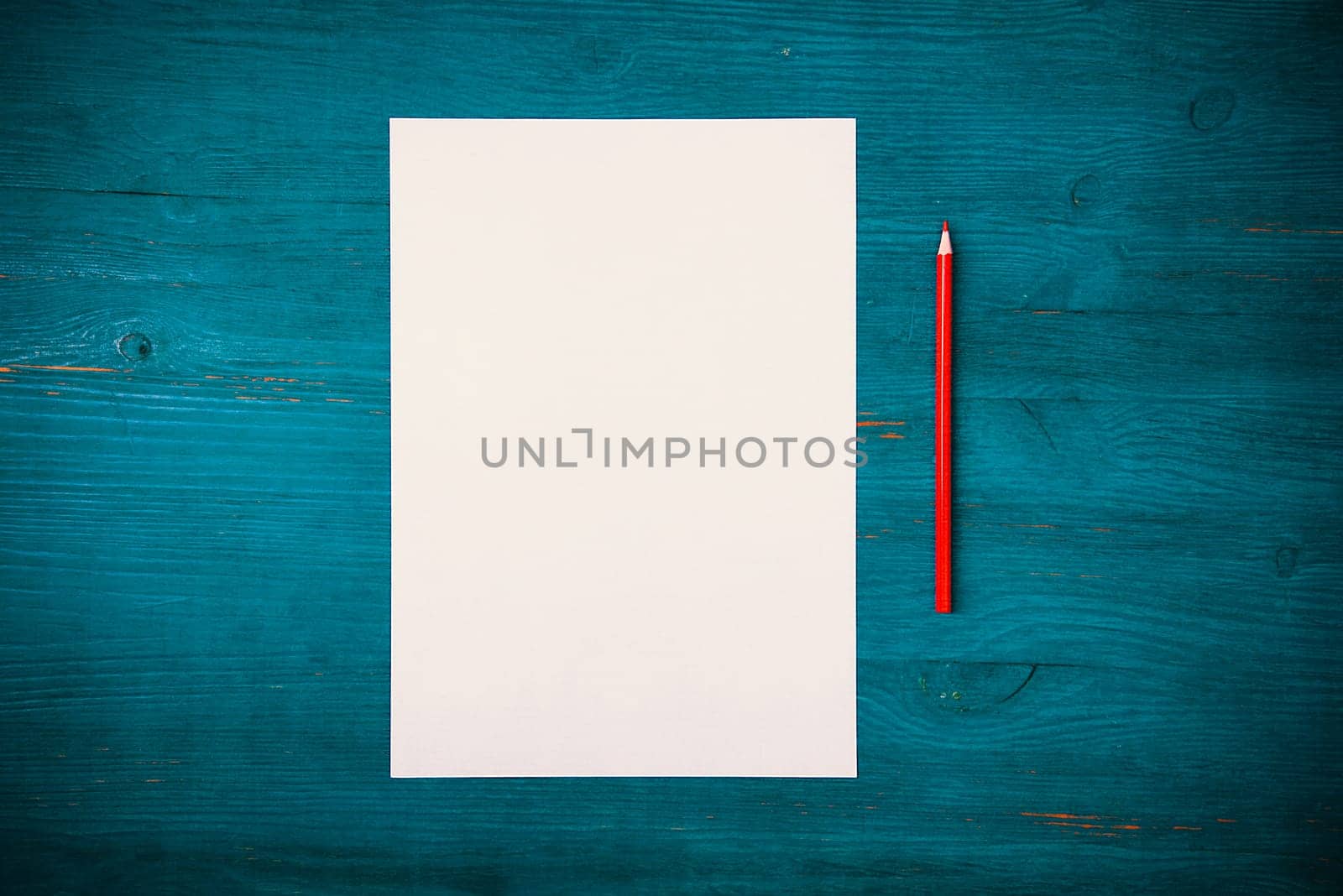 A blank white sheet and pencil for drawing on a wooden background with space for copying and lettering. Layout, mockup free space.