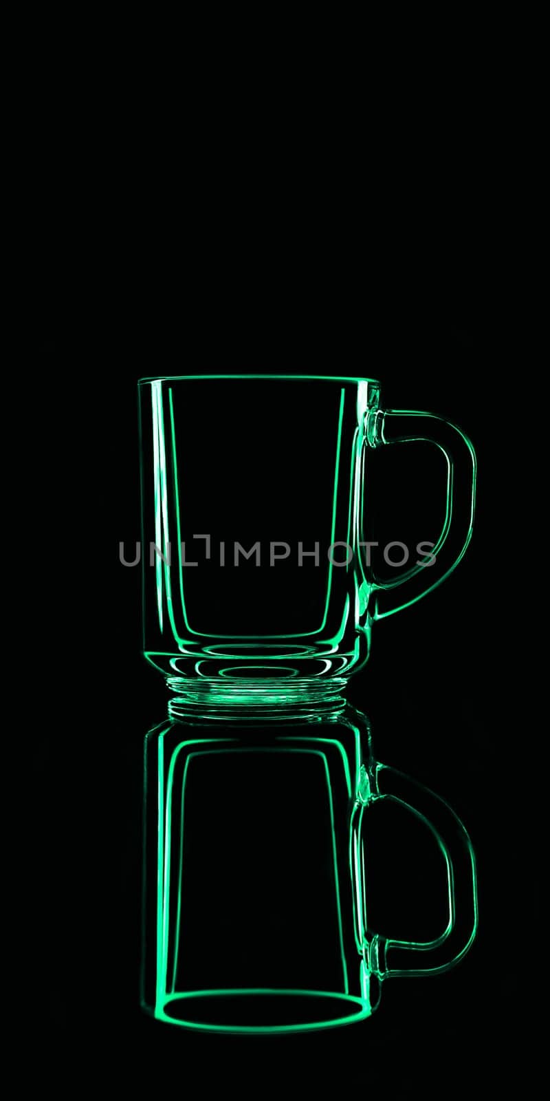 Just a glass on a black background with a reflection. Green colors. Isolated.