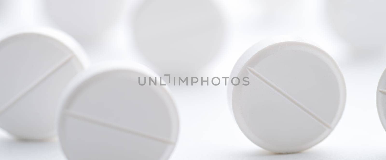 A pile of white pills scattered on a bright white background. Selective focus. Mockup layout, template.