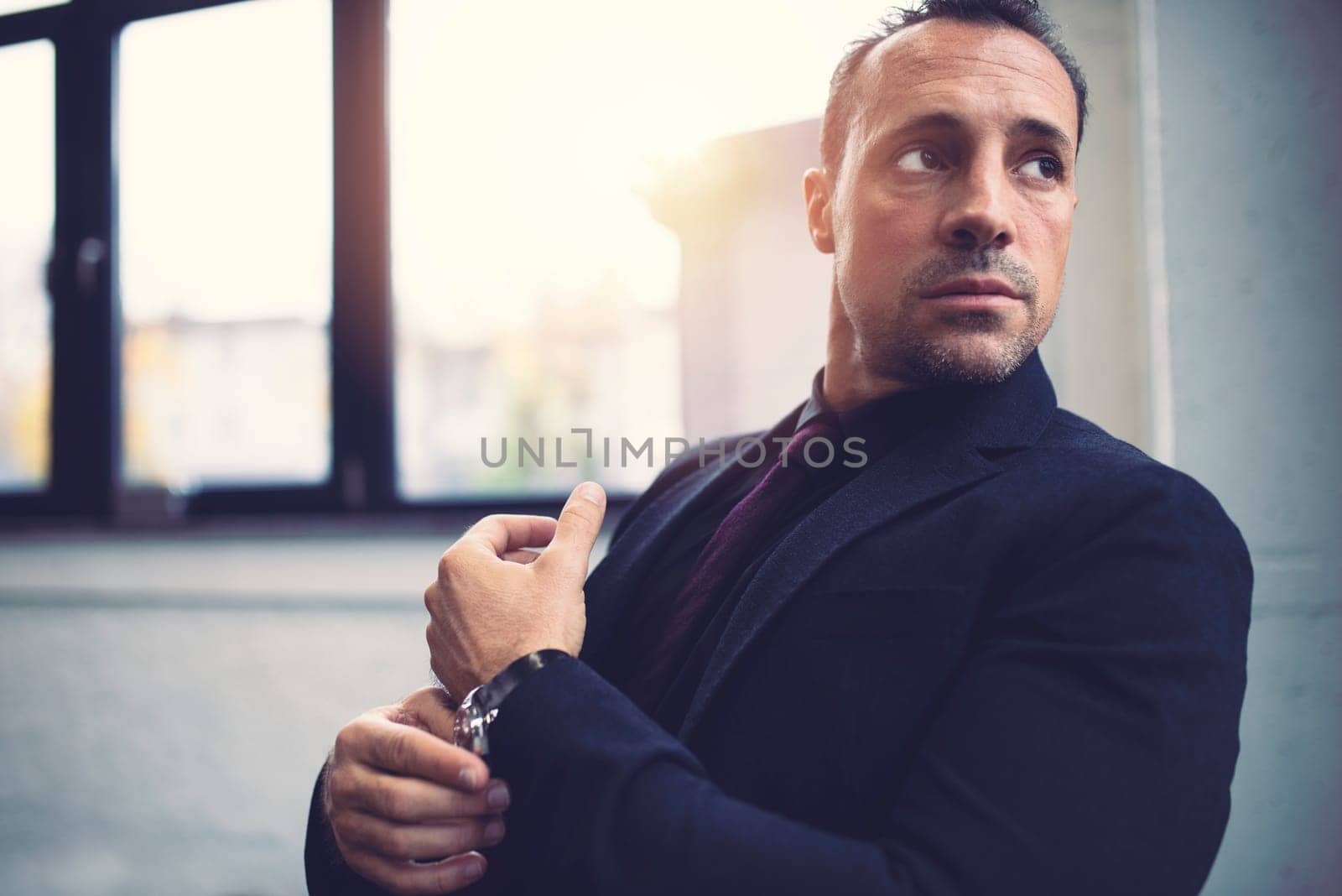 Pensive senior businessman against the window in a modern office