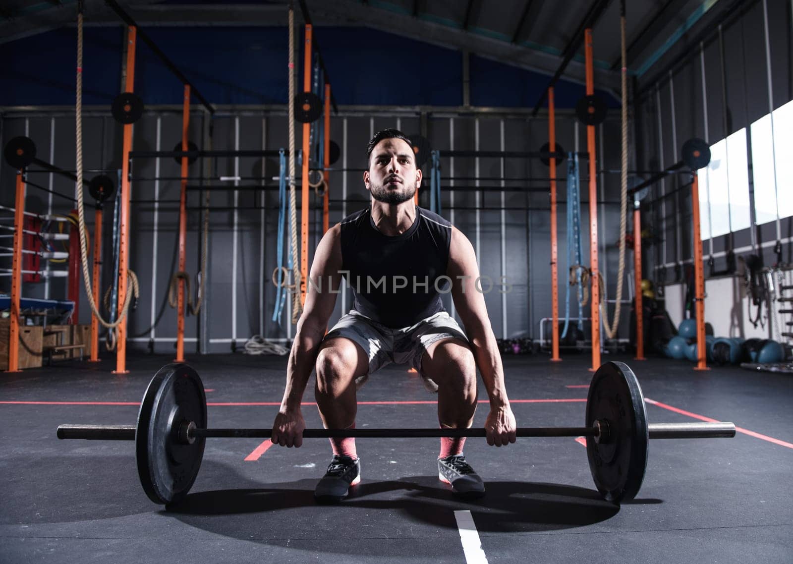 Determined athletic man works out at the gym with a barbell