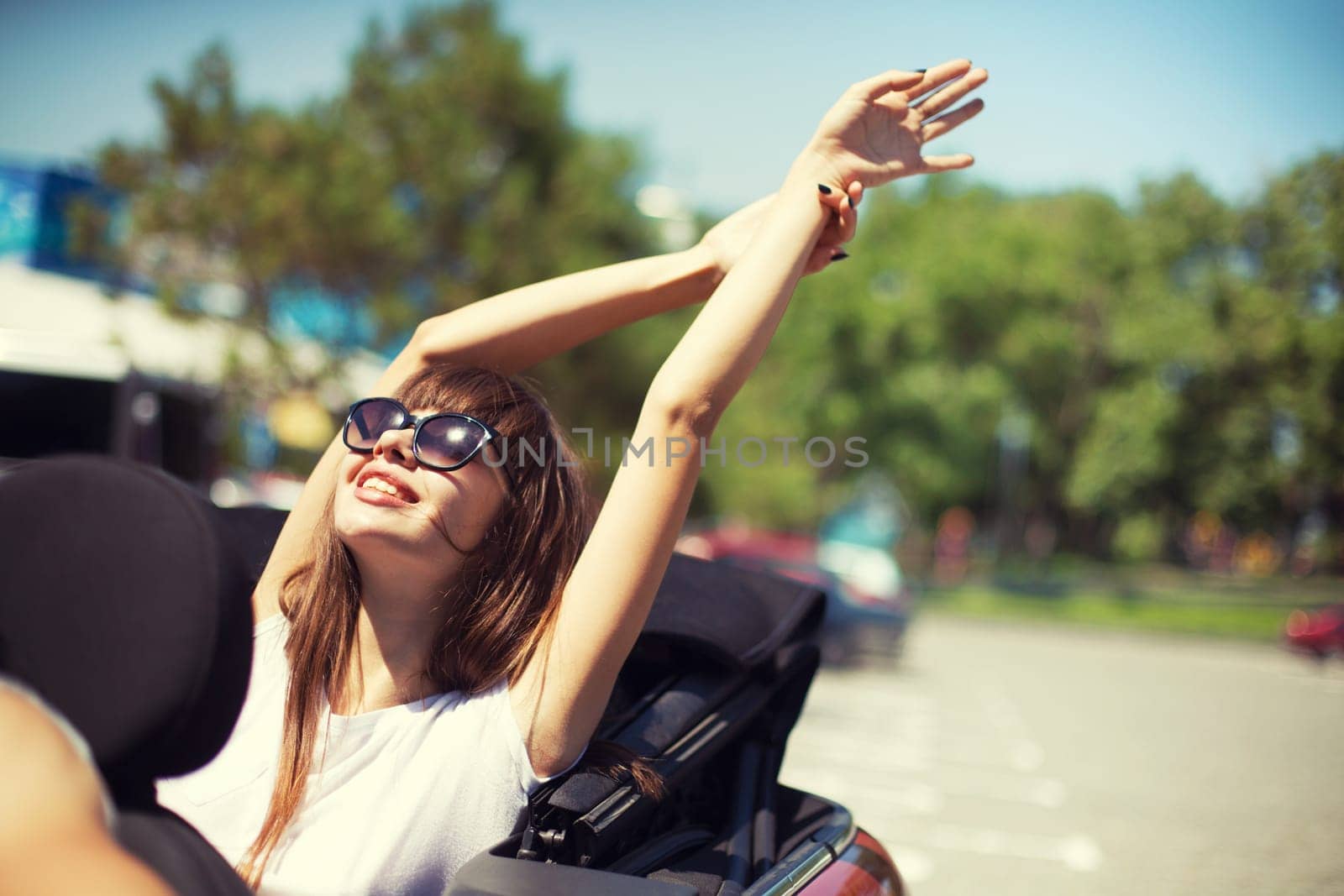 Young Caucasian woman in cabriolet car near sea departs for the summer holidays
