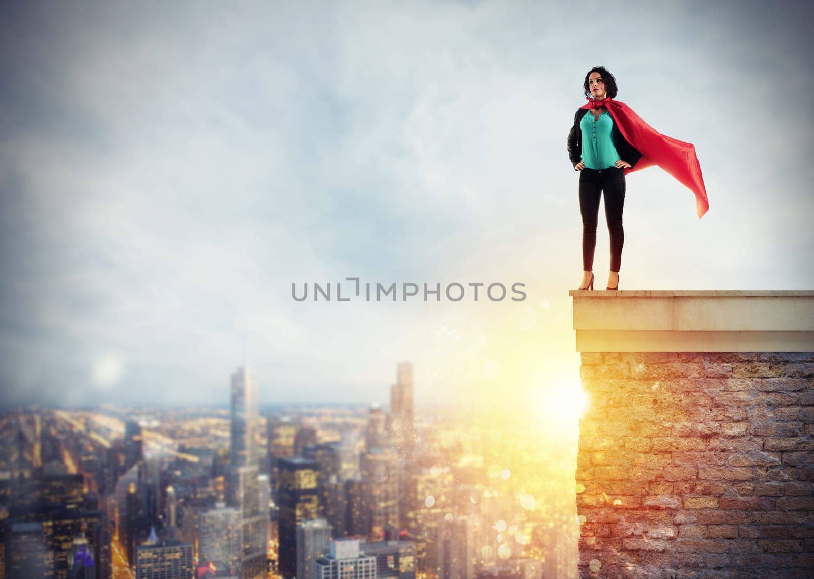 Successful businesswoman acts like a super hero above the roof of a building during sunrise. Concept of determination and success