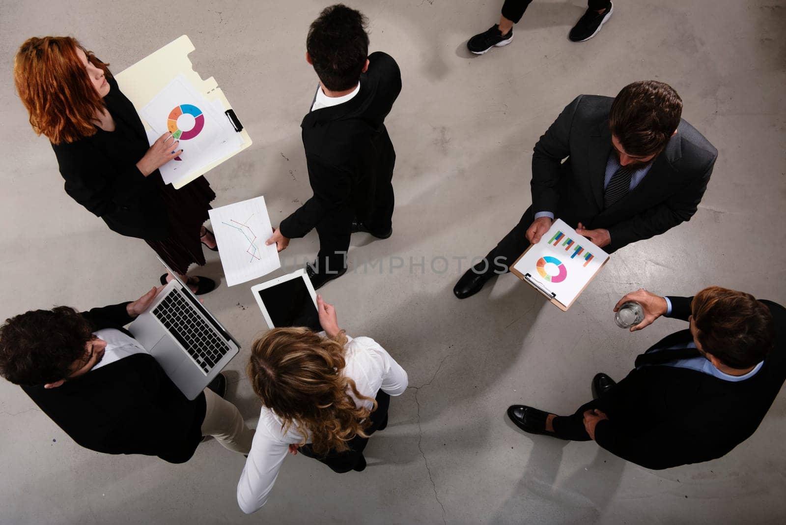 Team of people works together on company statistics in office. Shooted from above. Concept of teamwork and partnership