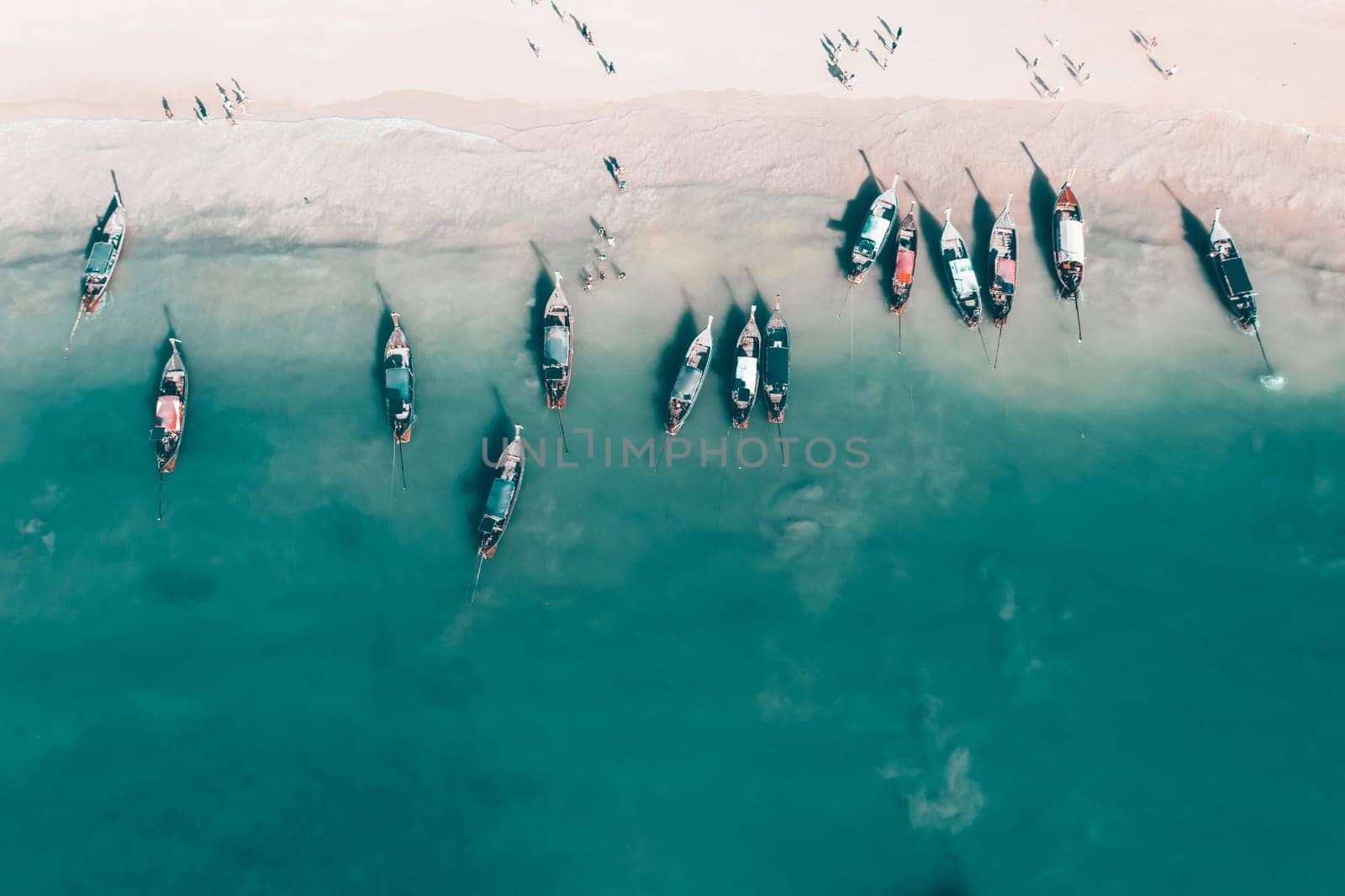 Aerial, drone view of a beautiful tropical beach with white sand, turquoise clear water and longtail boats near Krabi, Thailand.