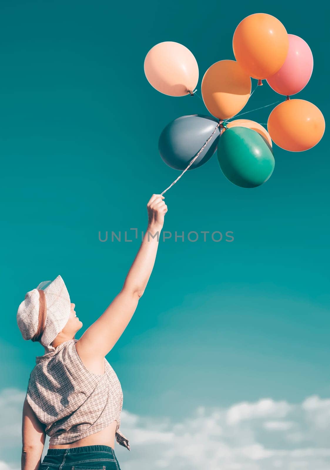 Young woman with colorful balloons in summer field - retro styled photo
