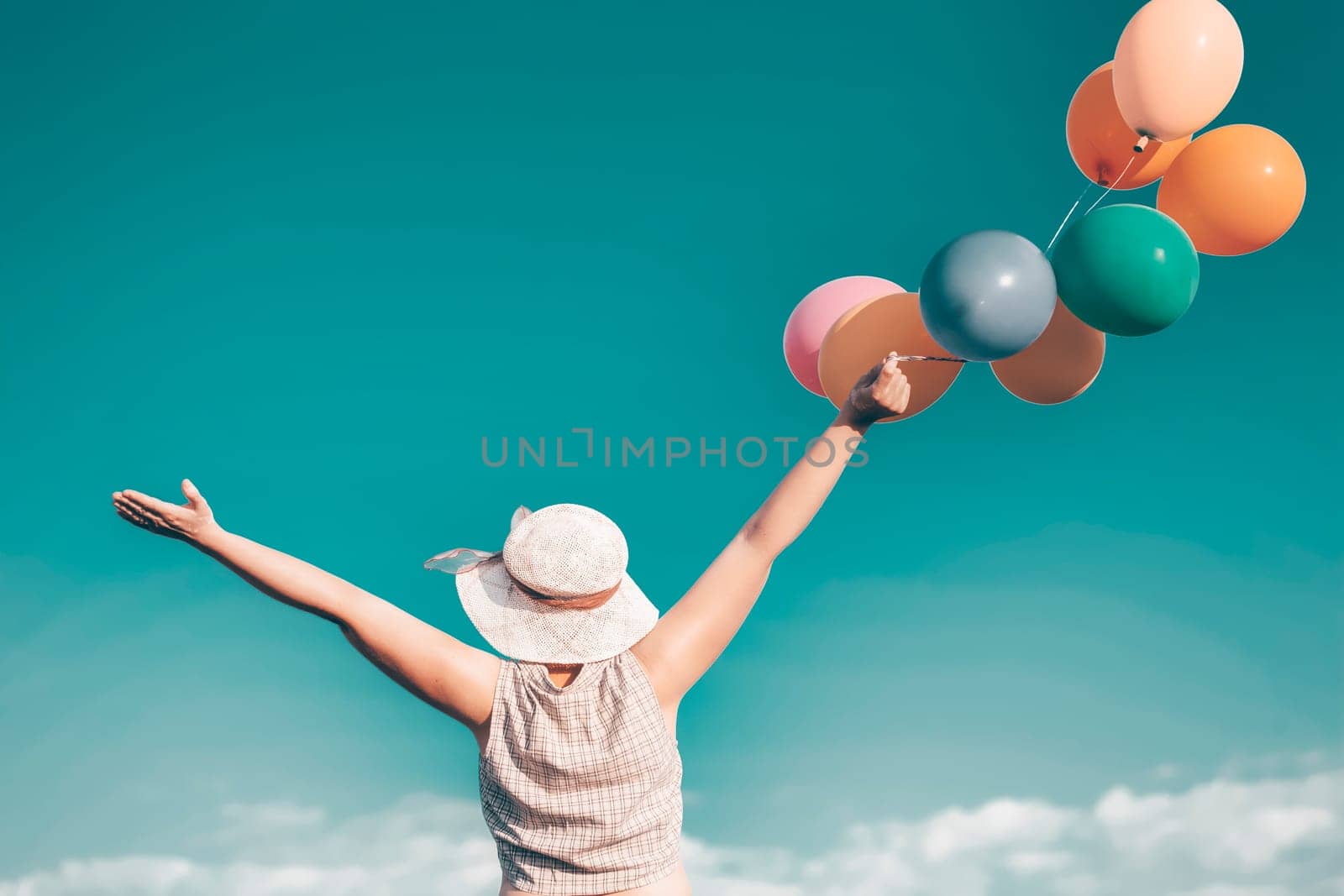 Young woman with colorful balloons in summer field - retro styled photo