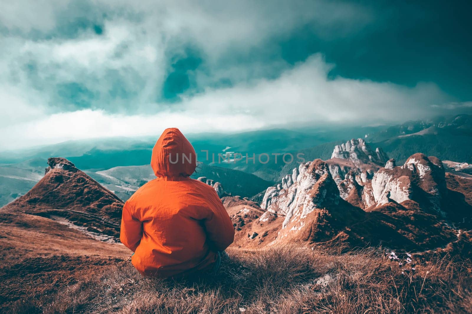 Woman sitting on cliff enjoying mountains landscape. Lifestyle concept. Traveling active adventure vacations.