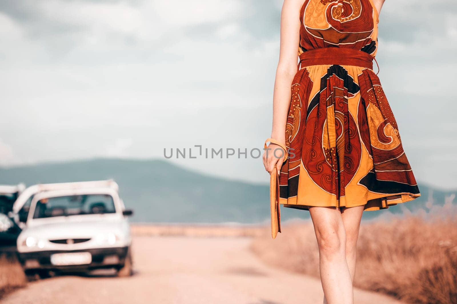 Closeup of happy young woman wearing light summer dress with flowers on sunny day outdoors