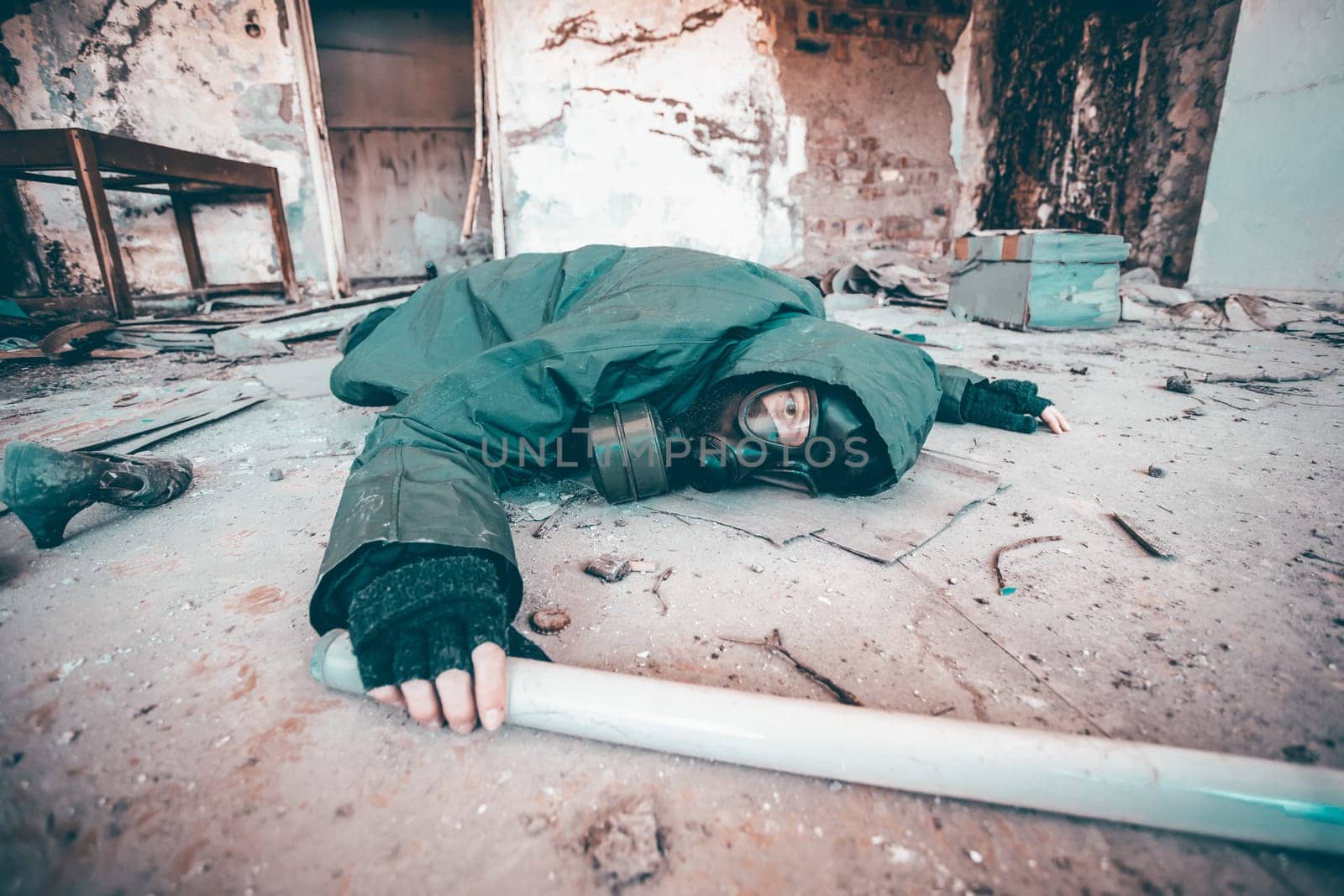 Post apocalyptic survivor in gas mask fallen on the ground in a ruined building. Environmental disaster, armageddon concept.