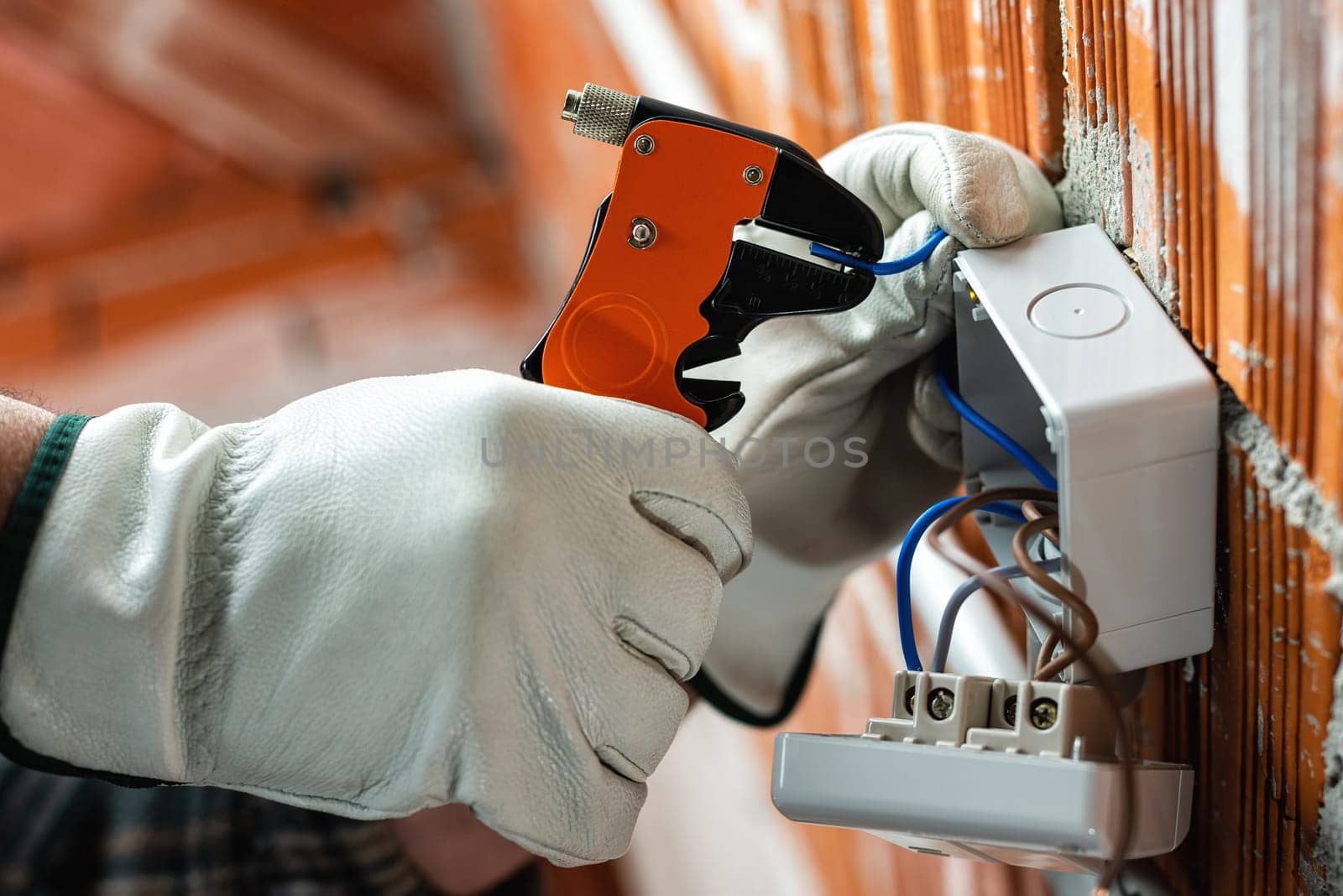 Bottom view. Electrician worker at work with wire stripper prepares the electrical cables of an electrical system. Working safely with protective gloves. Construction industry.