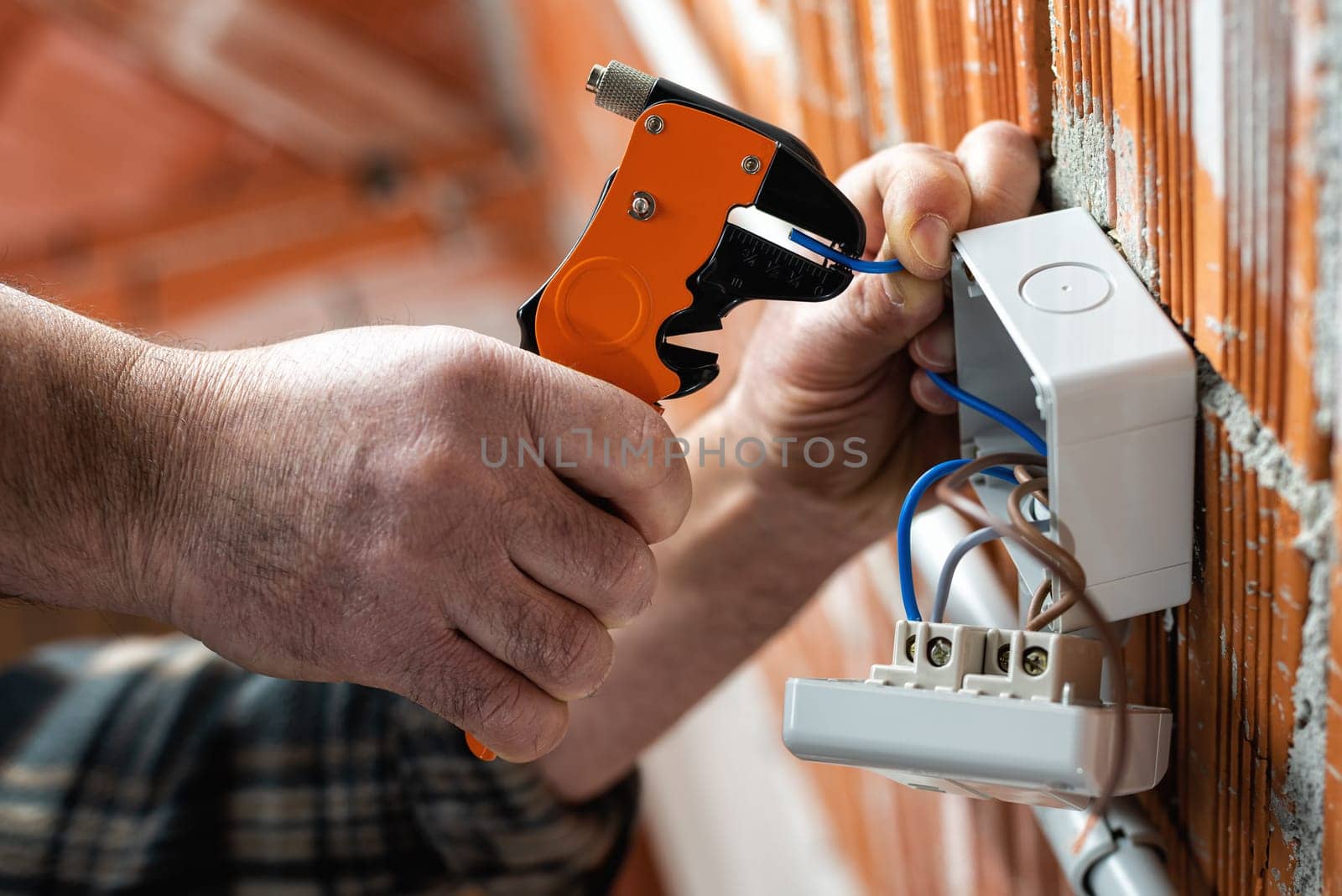 Bottom view. Electrician worker at work with wire stripper prepares the electrical cables of an electrical system. Construction industry.
