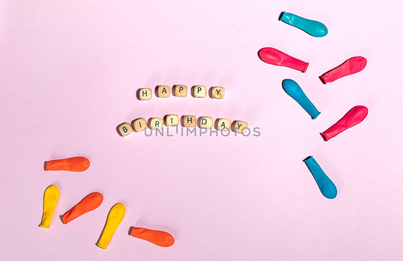 Flat lay minimal composition with colorful balloons and wooden bricks on pastel pink. Happy birthday concept