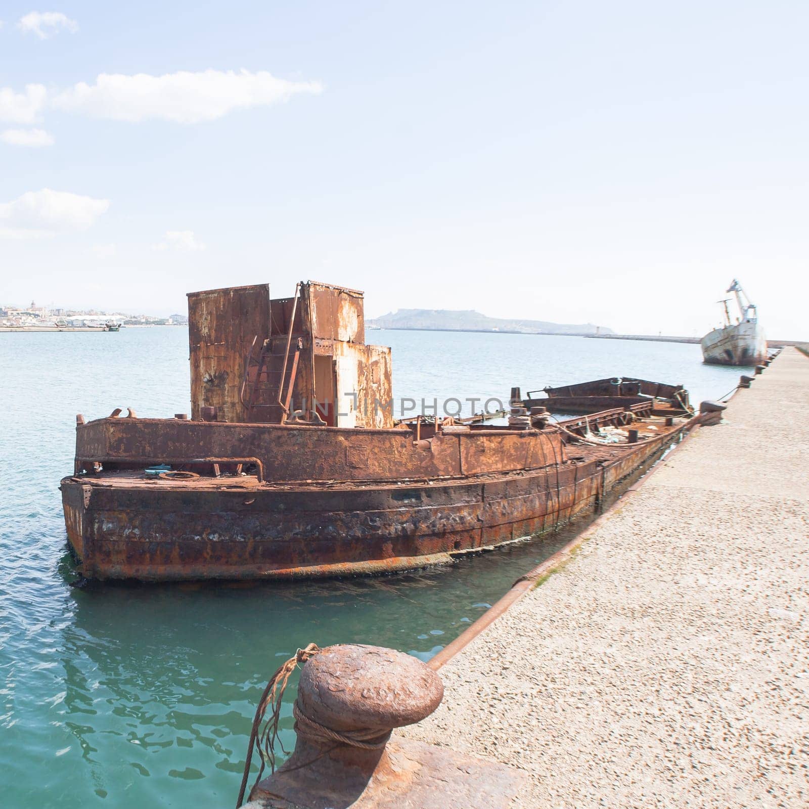 Rusty wreck moored, abandoned in the pier in the harbor of Cagliari Sardinia.