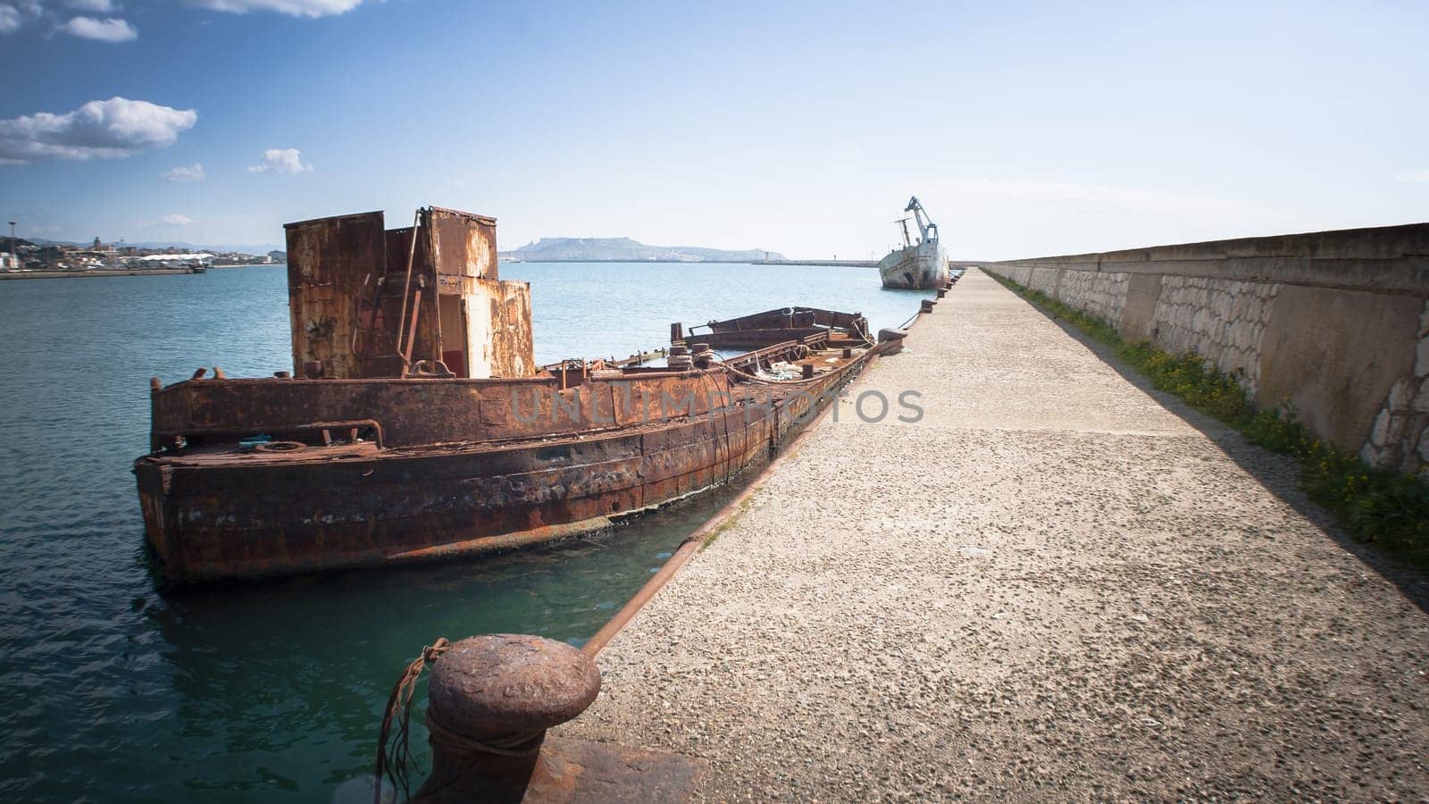 Rusty wreck moored, abandoned in the pier in the harbor of Cagliari Sardinia.