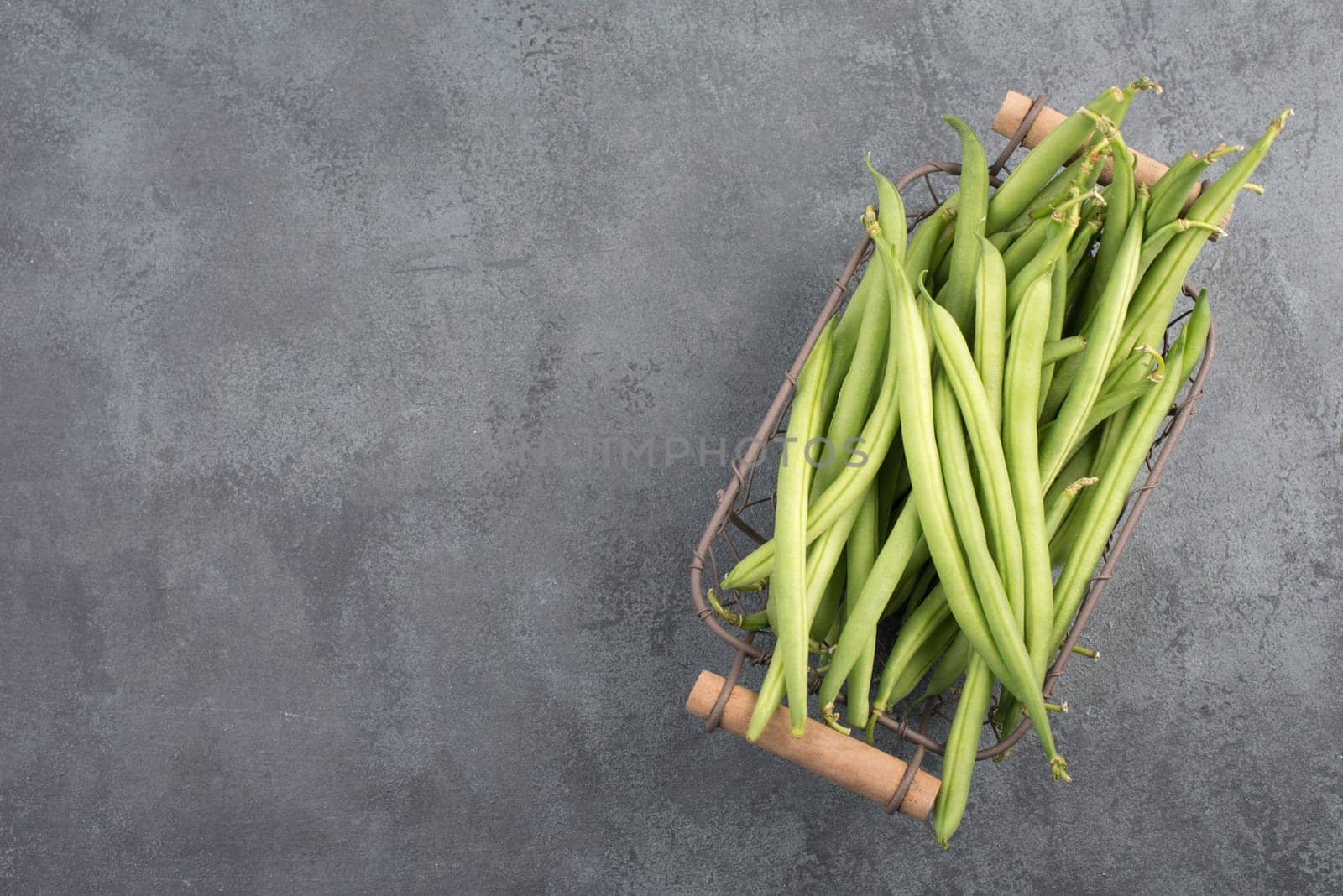 Green string beans on a textured background, empty space for text, fresh vegetables