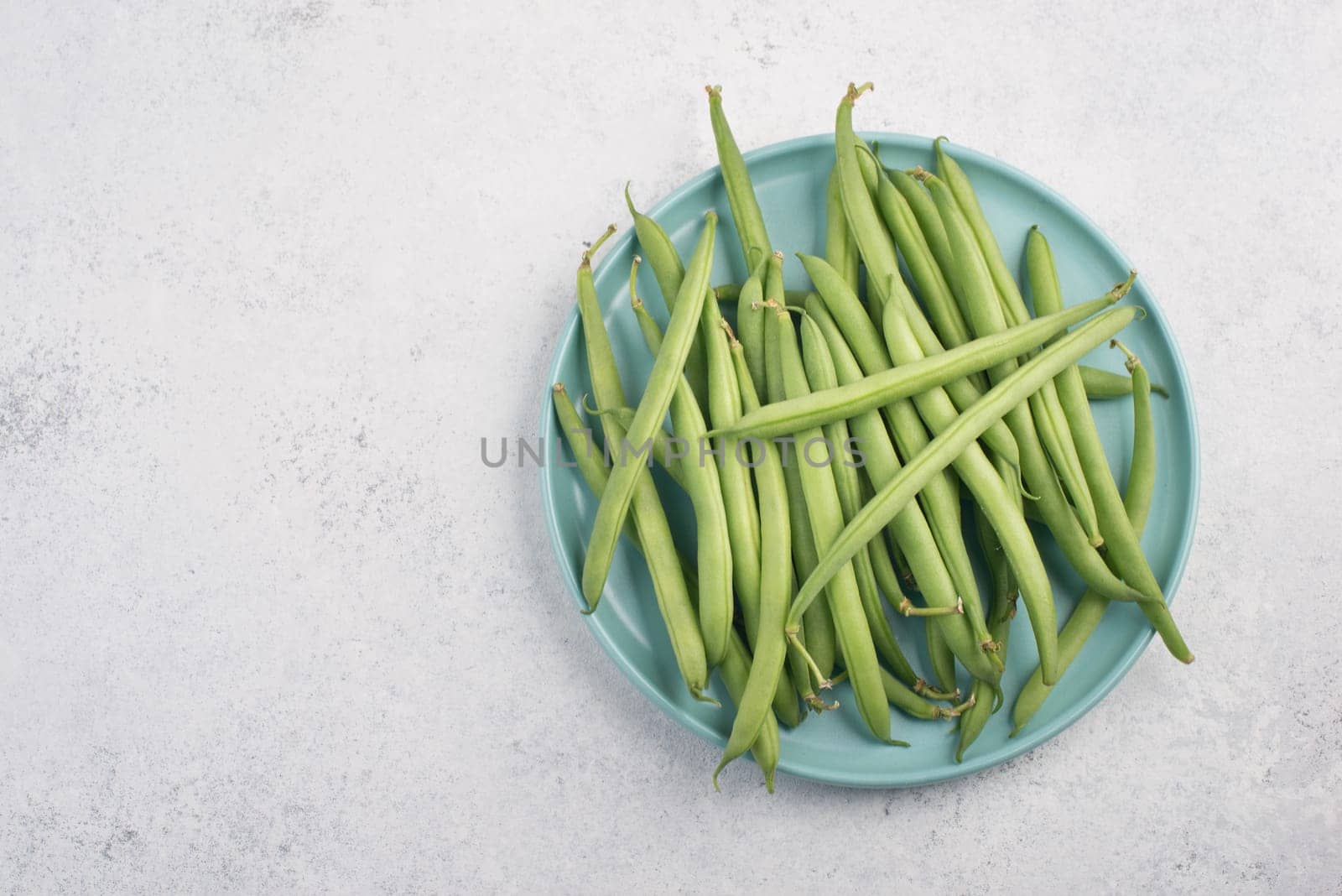 Green string beans on a textured background, empty space for text, fresh vegetables