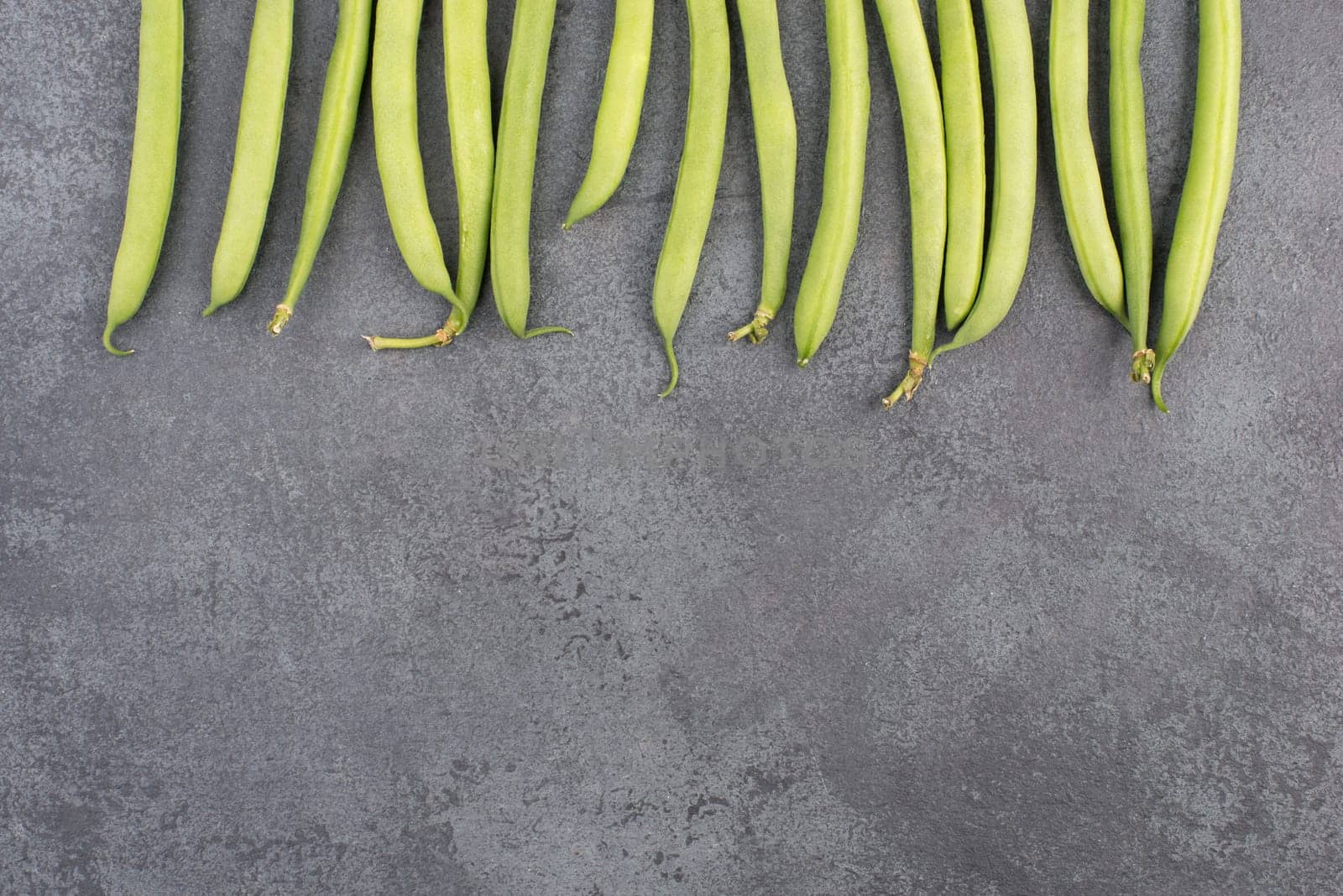 Green string beans on a textured background, empty space for text, fresh vegetables