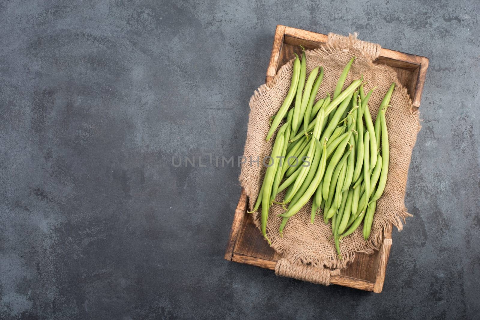 Green string beans on a textured background, empty space for text, fresh vegetables