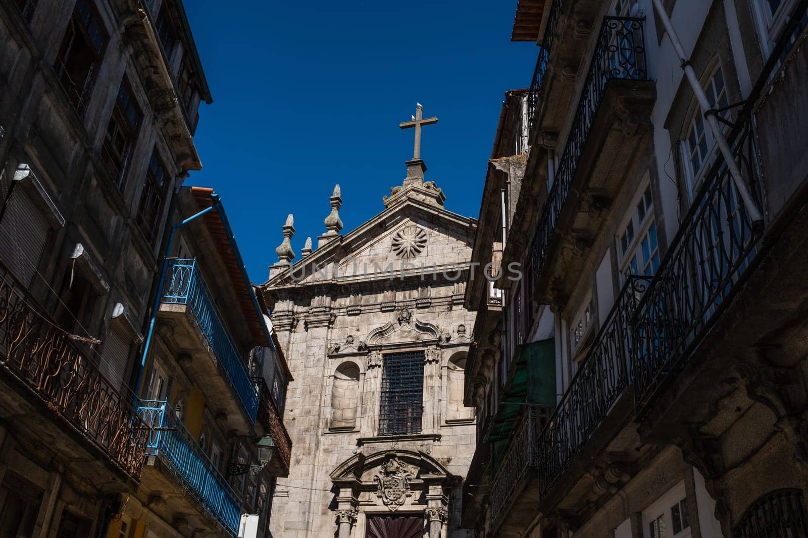 Porto, Portugal: partial view of Igreja de Nossa Senhora da Vitória (Our Lady of Victory Church) and old residential buildings seen from street level, in the afternoon summery light.