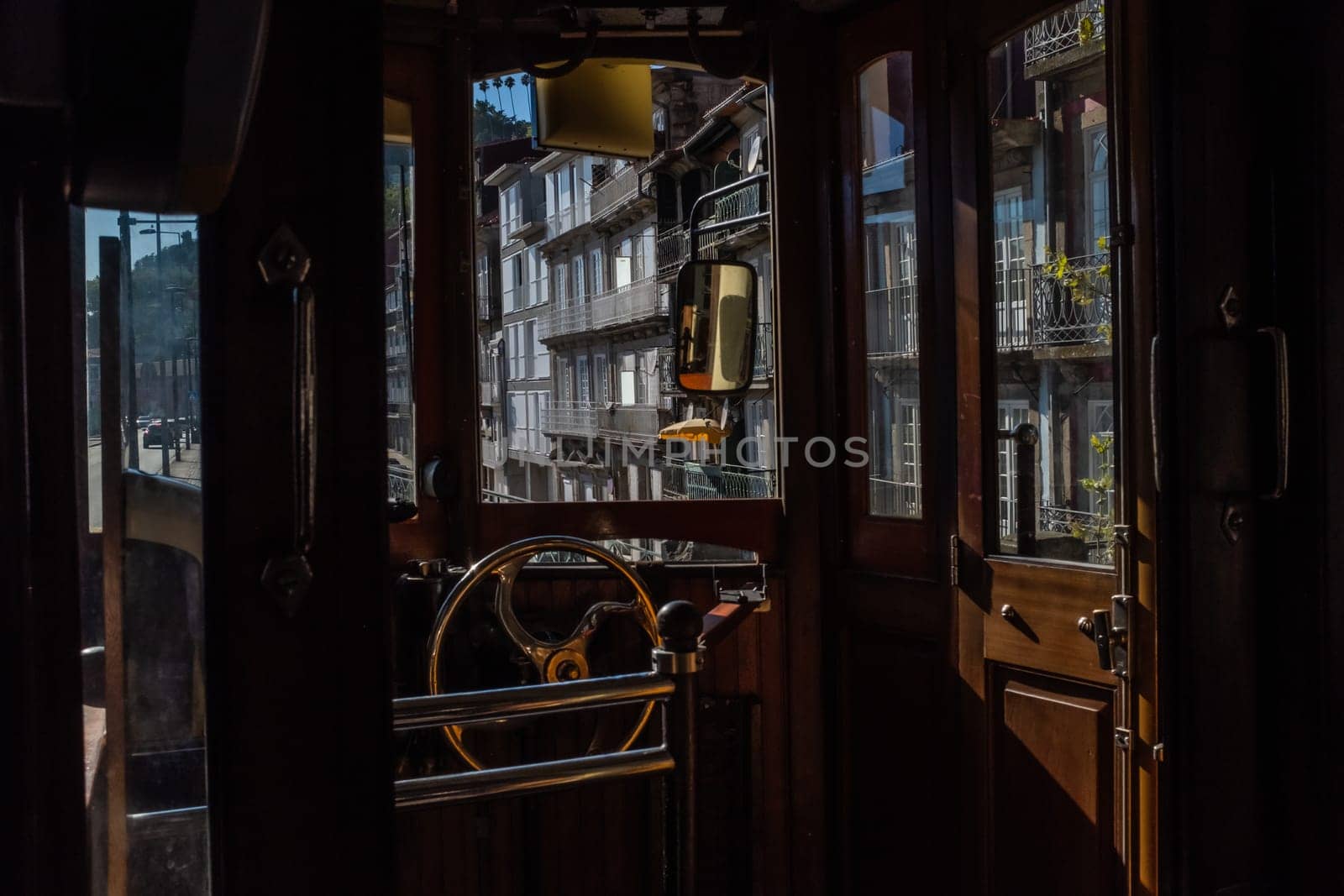 Interior of the rear cabin of one of Porto's historic trams still in service on line 1 and a fascinating view at the typical Portuguese facades through the windows. Retro charme of the design with wooden structure and bronze steering wheel.