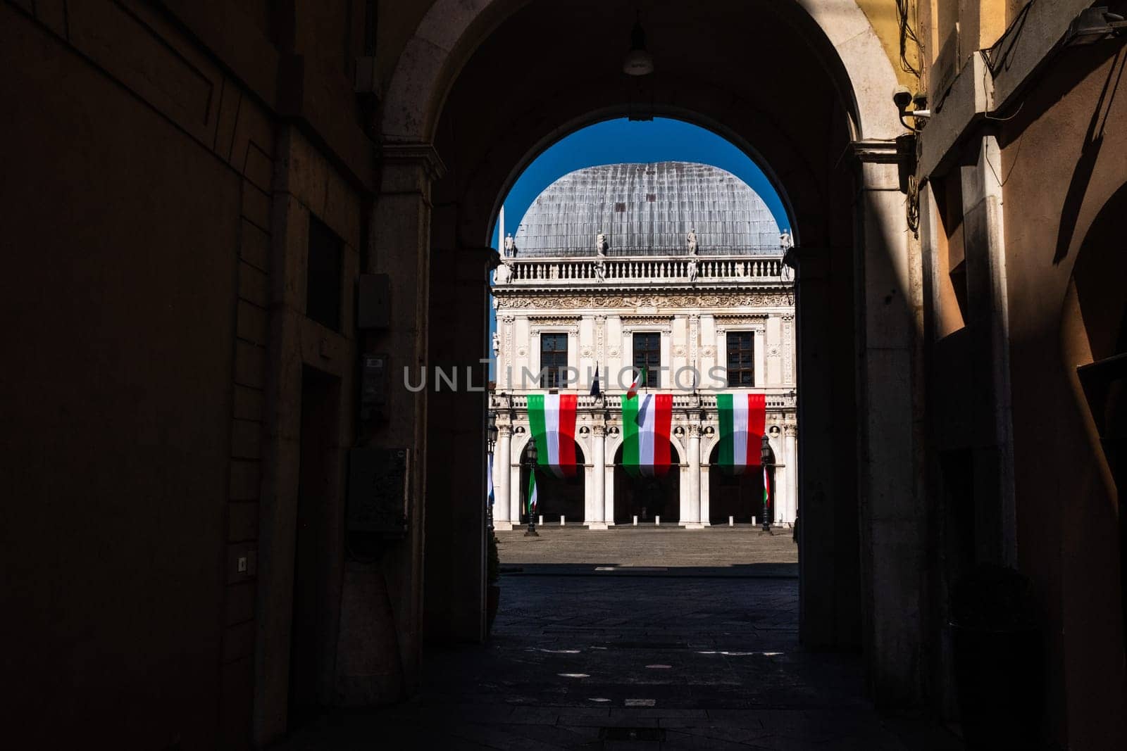 A suggestive view of the Palazzo della Loggia (Loggia Palace), seat of the Mayor of Brescia, decorated with large tricolor flags to celebrate the 75th anniversary of Italy's Liberation Day..This commemoration was atypical: Italy celebrated this important day in a state of emergency over the coronavirus outbreak.